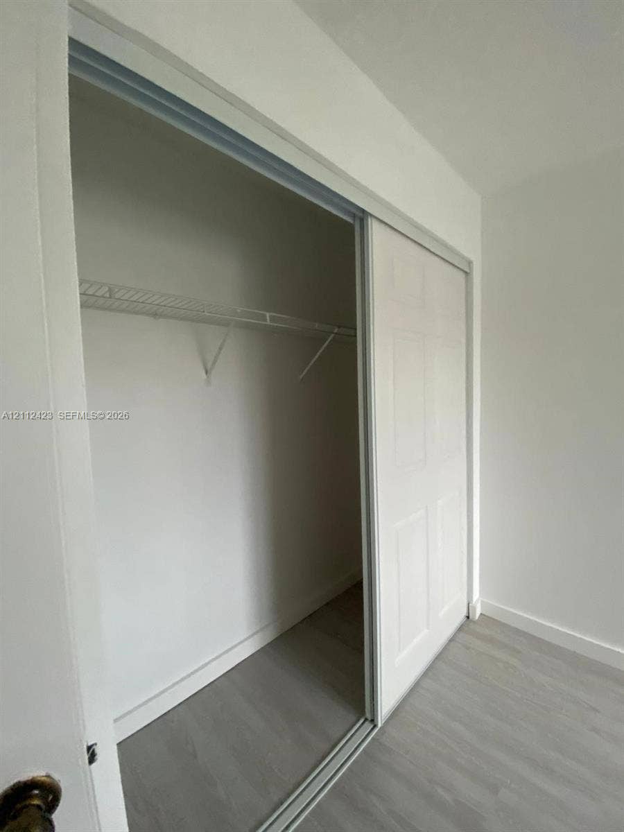 8555 SW 152nd Avenue, #104, Miami, FL 33193 Closet featuring white sliding doors and integrated wire shelving over wood-finish flooring