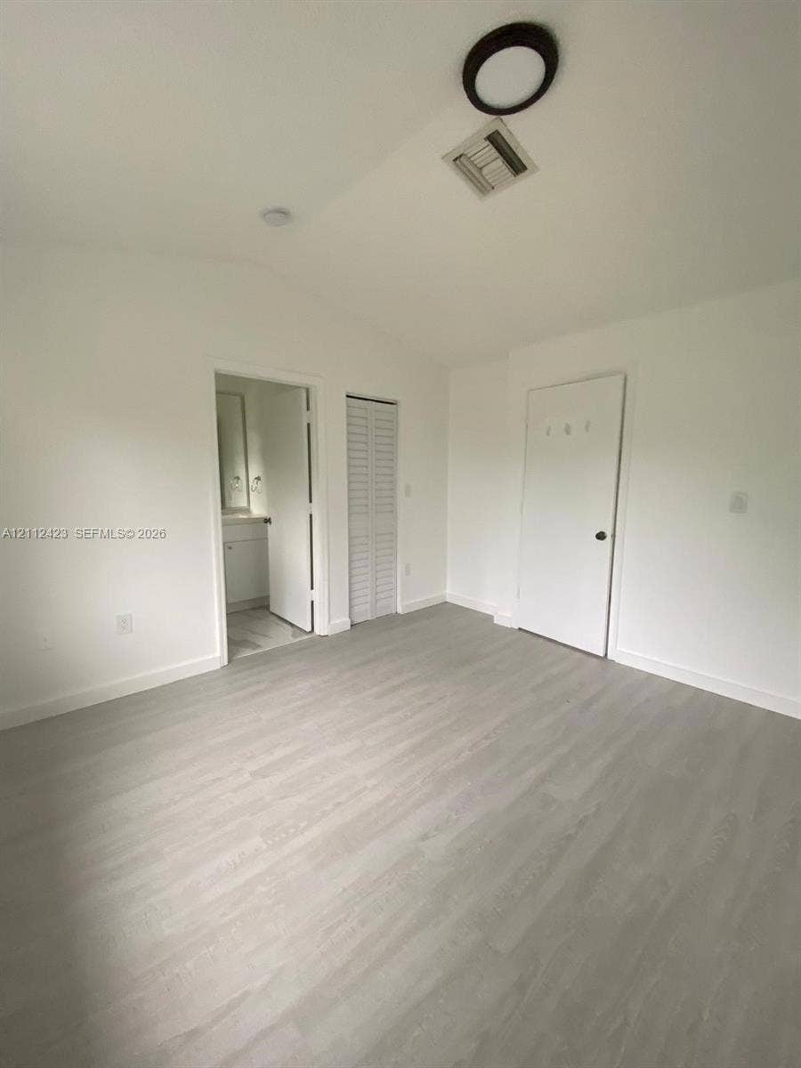 8555 SW 152nd Avenue, #104, Miami, FL 33193 Neutral-toned wood-finish flooring, vaulted ceilings, and louvered closet doors