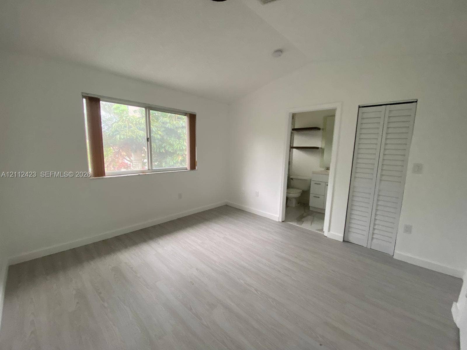 8555 SW 152nd Avenue, #104, Miami, FL 33193 Interior space featuring wood-finish flooring, a sliding window with horizontal blinds, and a built-in closet with louvered bifold doors
