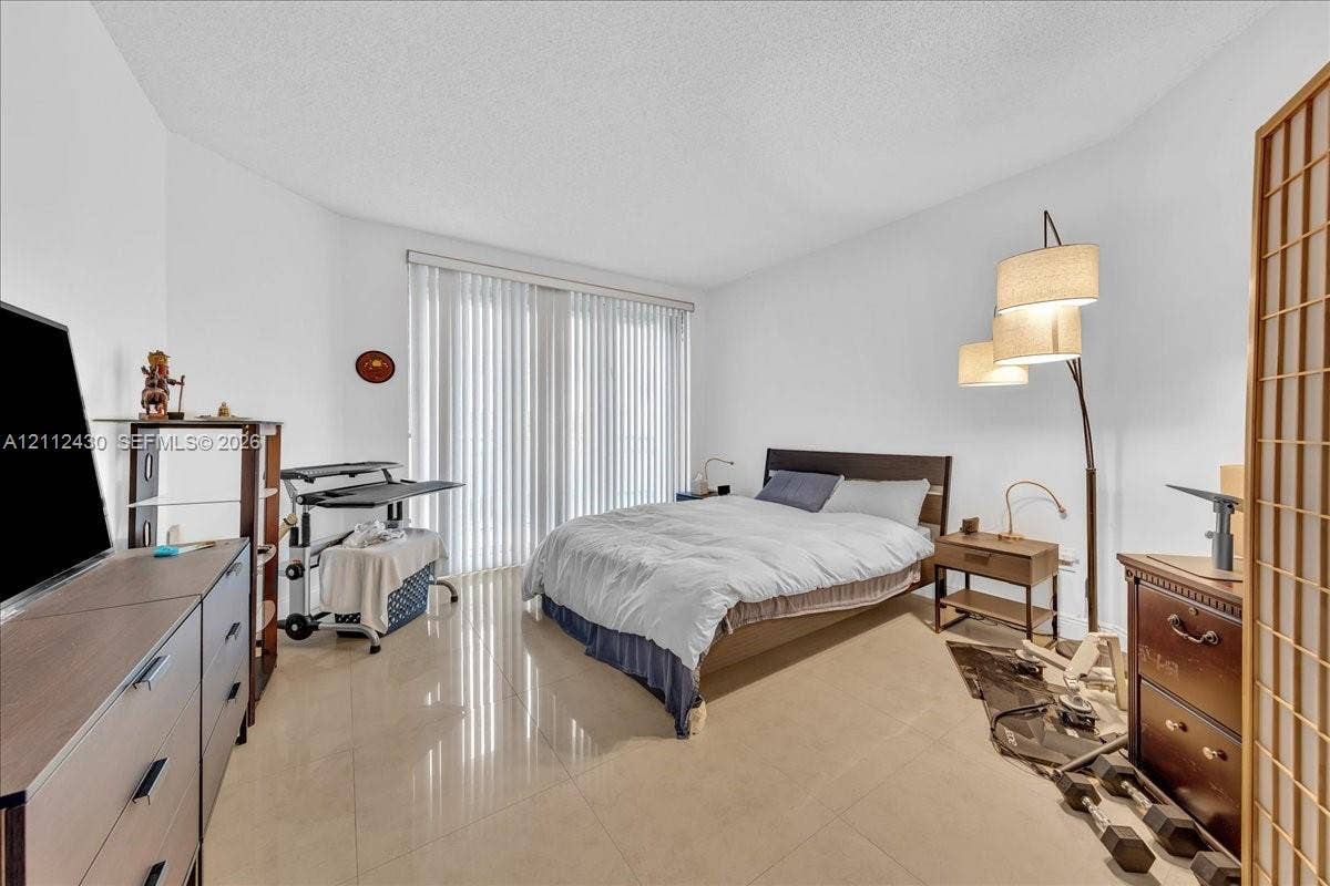 Spacious interior featuring large-format tile flooring and floor-to-ceiling vertical blinds