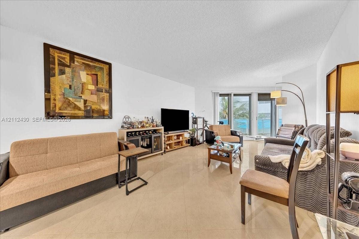 Living area featuring large-format ceramic tile flooring and floor-to-ceiling glass sliding doors