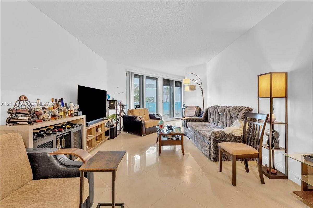 Living area featuring polished tile flooring, neutral walls, and large floor-to-ceiling glass sliding doors