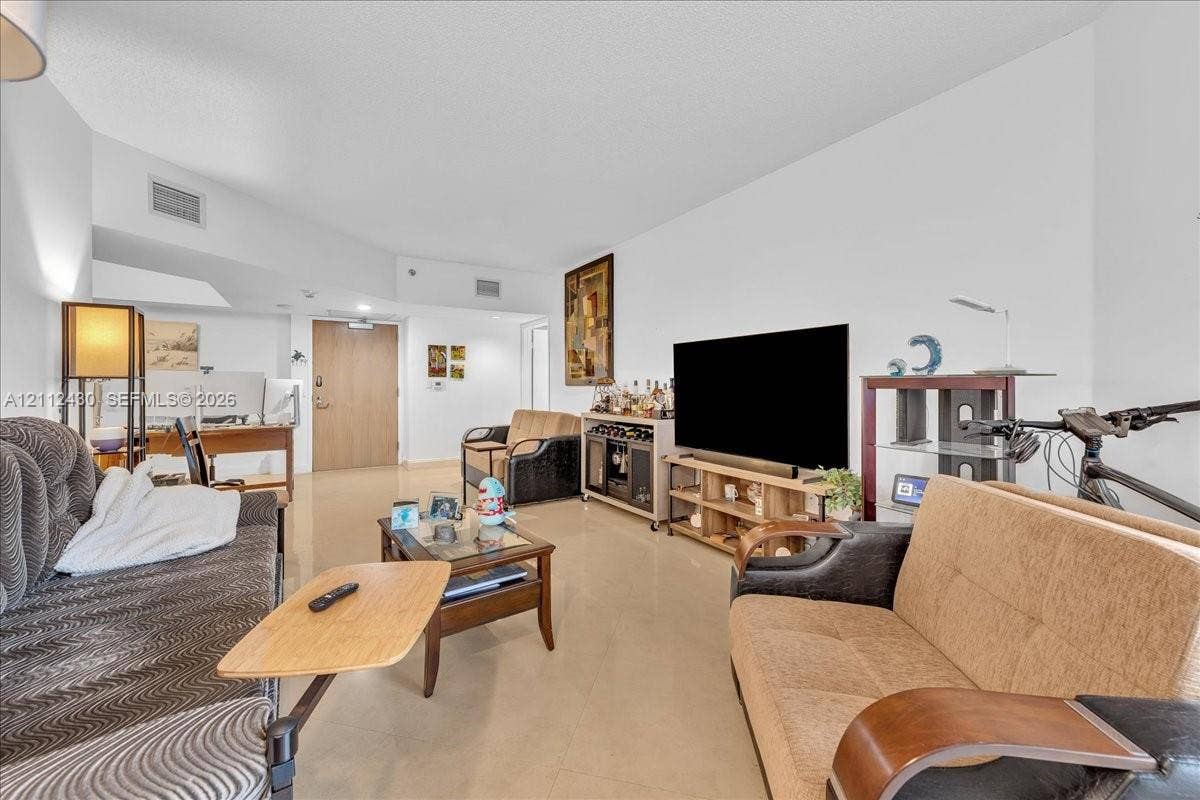 Open-concept interior featuring neutral-toned tile flooring and vaulted ceilings