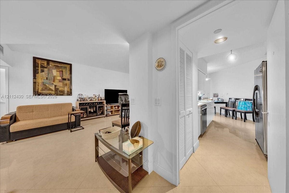 Large-format tile flooring, recessed ceiling lighting, and built-in louvered-door closet