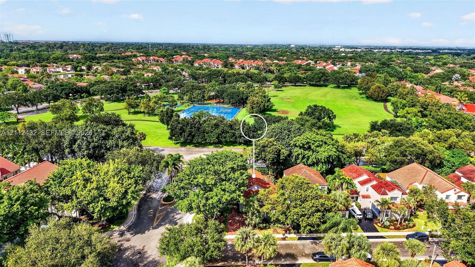 10545 NW 11th Court, Plantation, FL 33322 Aerial perspective featuring a residential lot with mature trees, a red-tiled roof, and proximity to expansive green space and a community recreational area