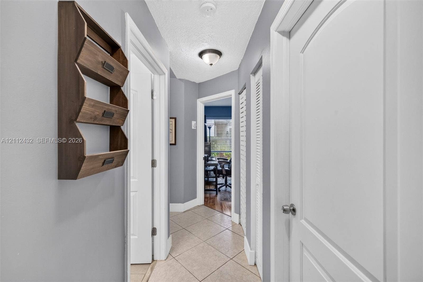 10545 NW 11th Court, Plantation, FL 33322 Hallway featuring neutral-toned walls, tile flooring, multi-panel interior doors, and a ceiling-mounted light fixture