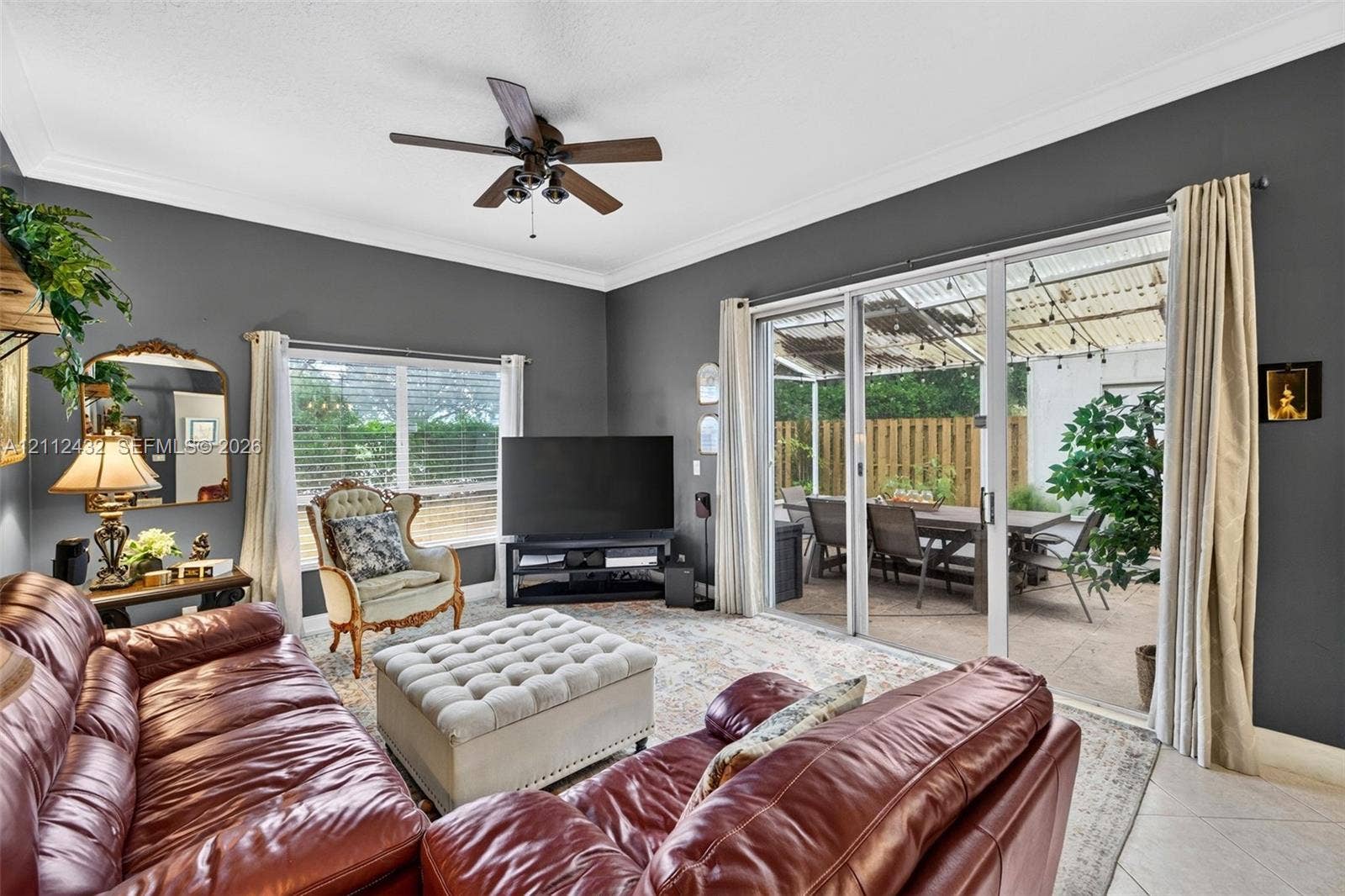 10545 NW 11th Court, Plantation, FL 33322 Living area featuring tile flooring, crown molding, a ceiling fan, and large sliding glass doors opening to a covered patio