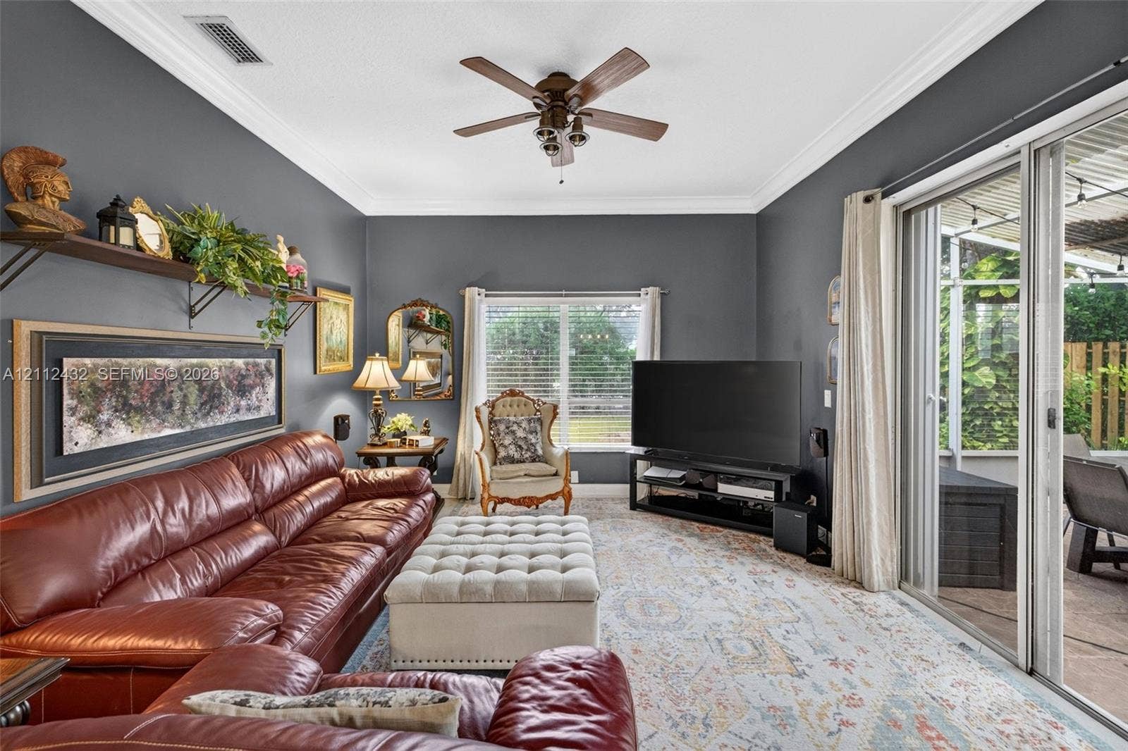 10545 NW 11th Court, Plantation, FL 33322 Living space featuring crown molding, neutral wall color, a multi-blade ceiling fan, and sliding glass doors