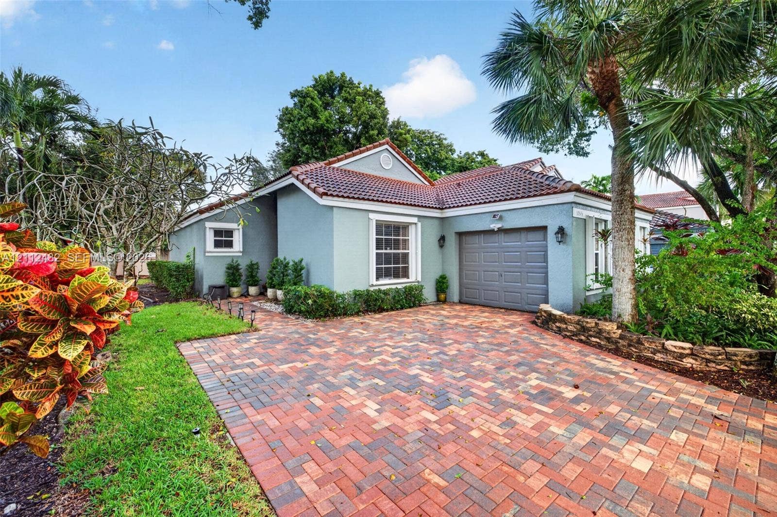 10545 NW 11th Court, Plantation, FL 33322 Single-story exterior featuring a multi-toned brick paver driveway, tile roof, and stone-accented landscaping