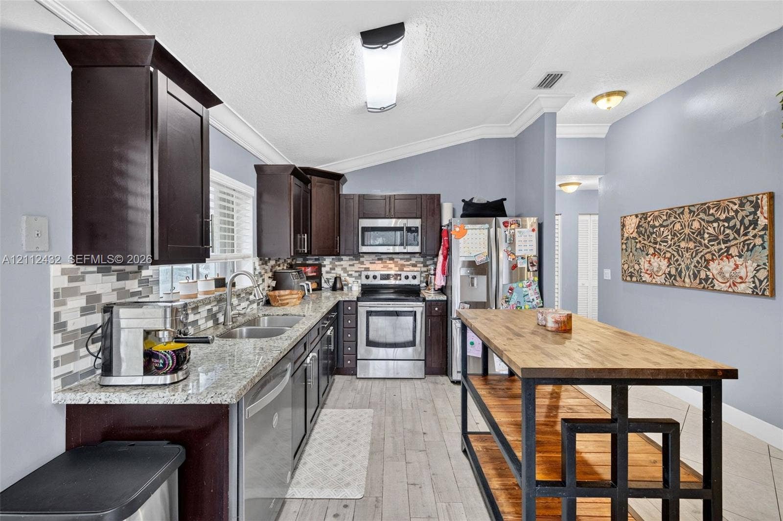 10545 NW 11th Court, Plantation, FL 33322 Kitchen featuring dark cabinetry, stone countertops, a multi-tone tile backsplash, stainless appliances, and wood-look tile flooring