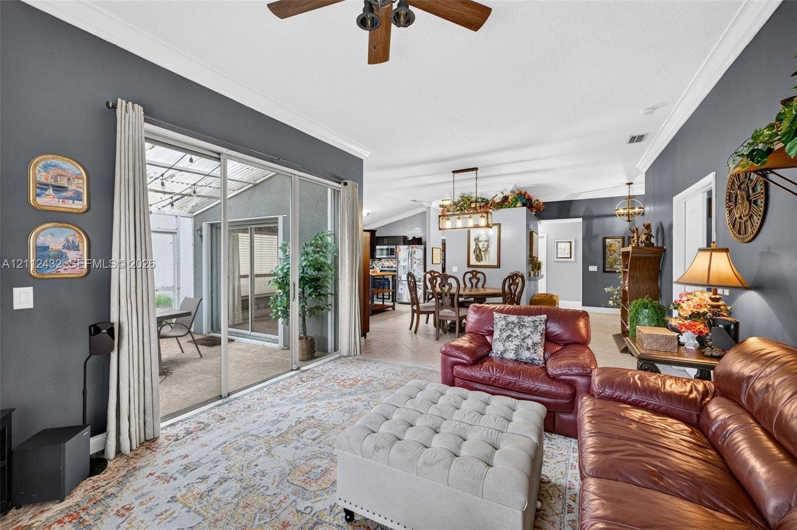 10545 NW 11th Court, Plantation, FL 33322 Living area featuring crown molding, neutral tile flooring, a multi-blade ceiling fan, and sliding glass doors opening to a covered patio