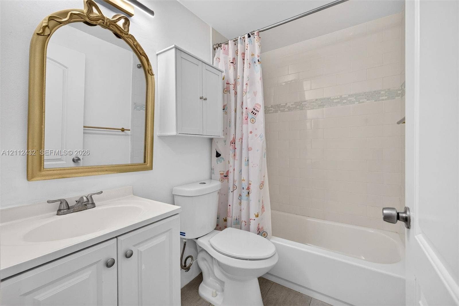 10545 NW 11th Court, Plantation, FL 33322 Bathroom featuring a white vanity cabinet with an integrated sink, a wall-mounted storage cabinet, a bathtub with tile surround, and an arched wall mirror