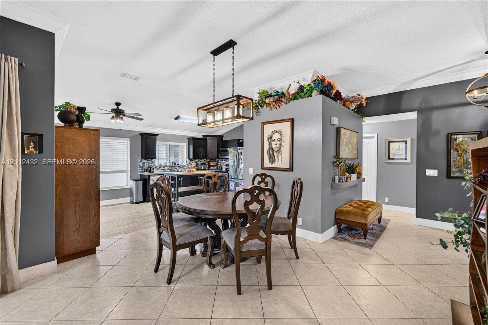 10545 NW 11th Court, Plantation, FL 33322 Open-concept interior featuring light-toned tile flooring, a central decorative wall divider, a rectangular multi-light pendant fixture, and crown molding