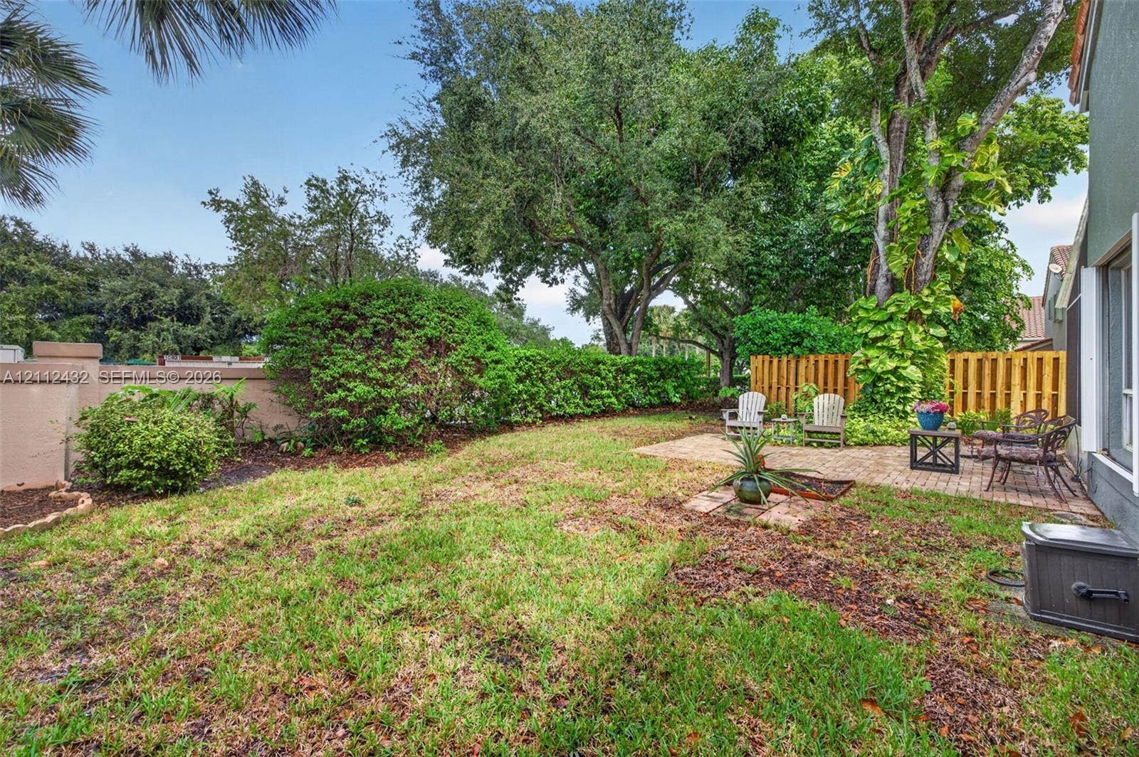 10545 NW 11th Court, Plantation, FL 33322 Private backyard featuring a paved stone patio, mature canopy trees, sculpted shrubbery