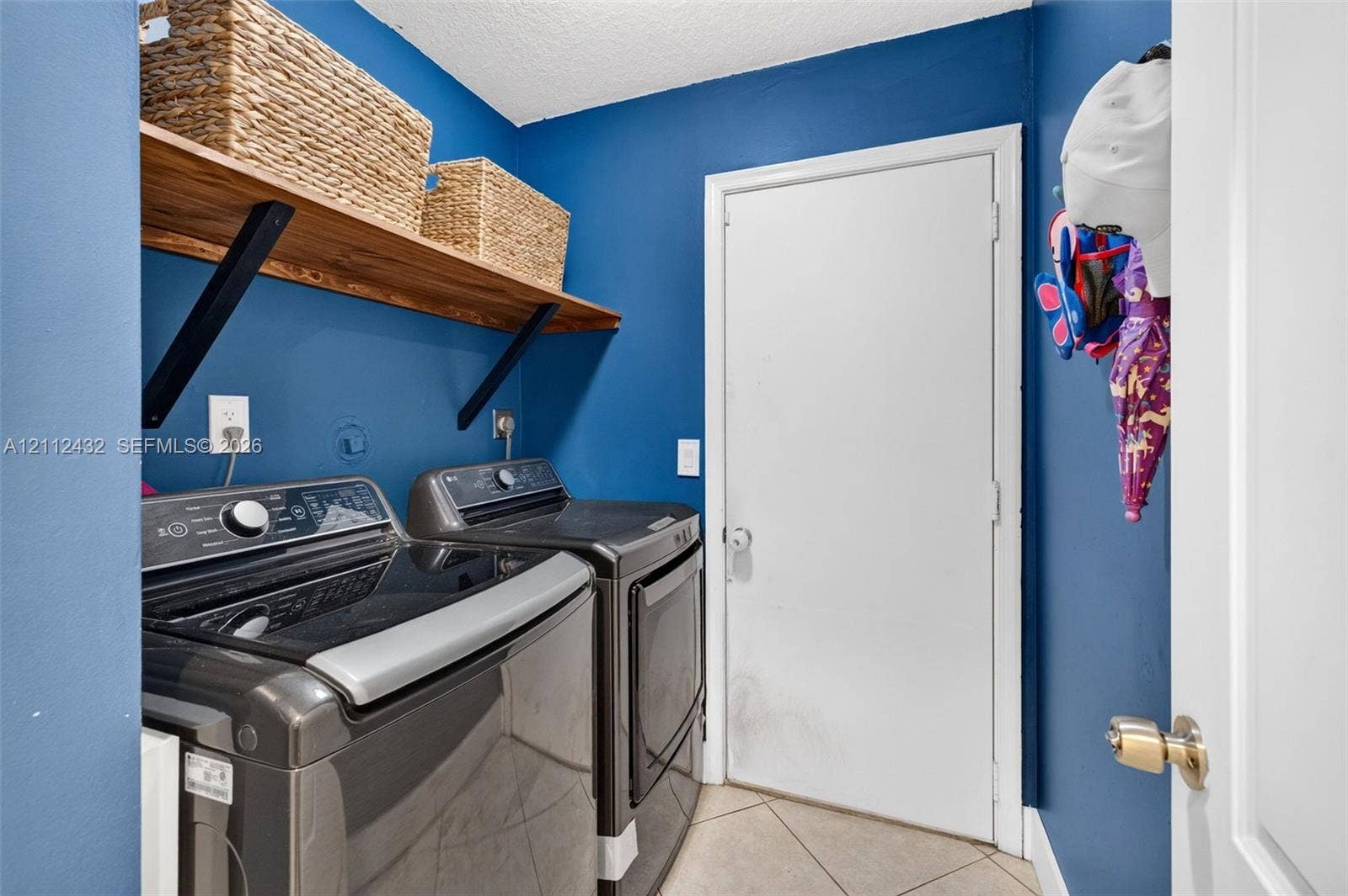 10545 NW 11th Court, Plantation, FL 33322 Laundry area featuring large-format diagonal tile flooring, mounted natural wood look shelving
