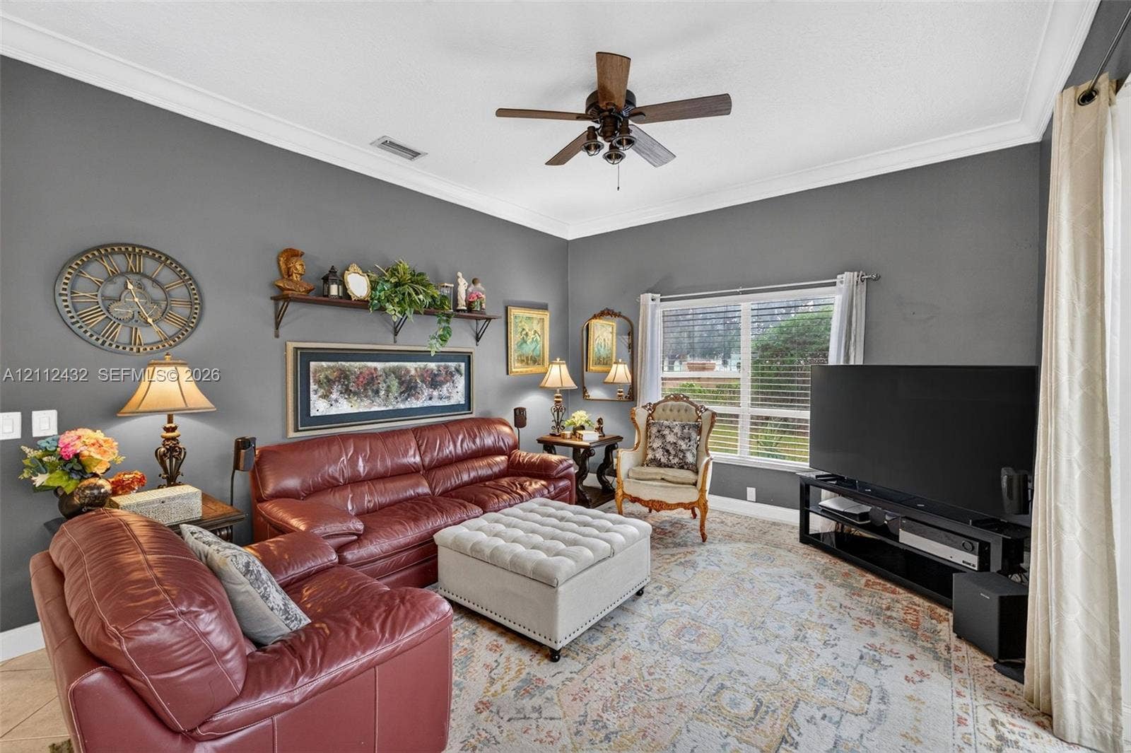 10545 NW 11th Court, Plantation, FL 33322 Living area featuring crown molding, neutral wall finishes, tile flooring, and a ceiling-mounted fan with integrated lighting