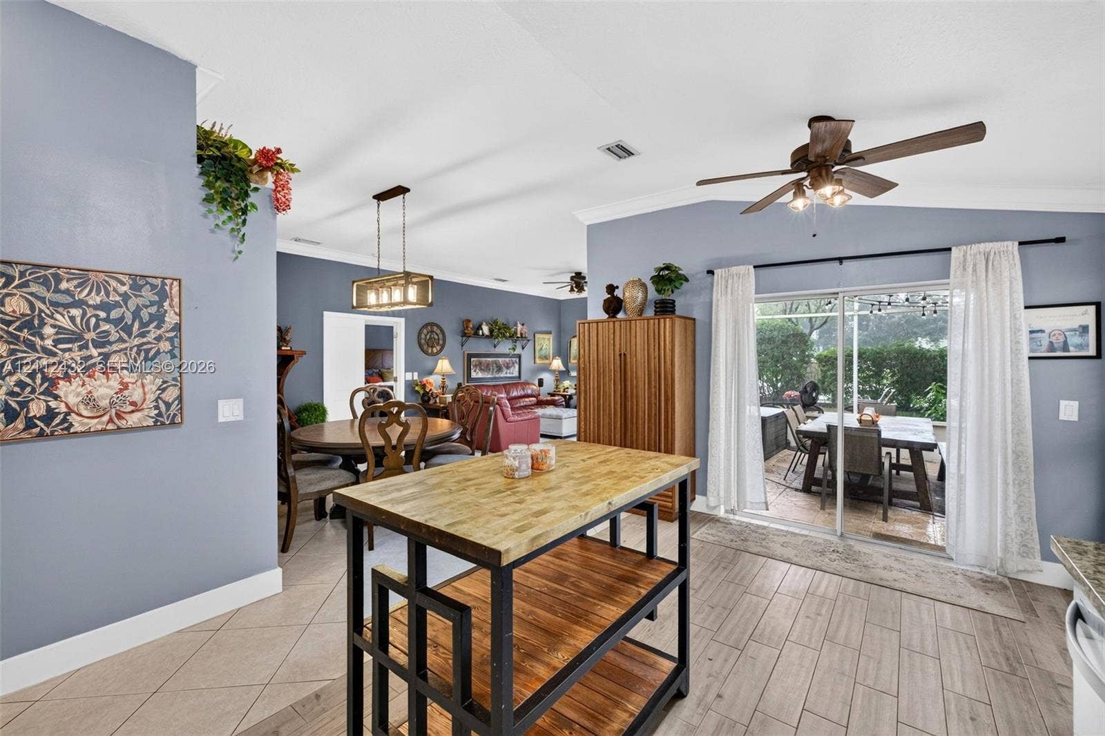 10545 NW 11th Court, Plantation, FL 33322 Open kitchen area featuring vaulted ceilings, wood-look tile flooring, sliding glass doors, and a multi-light metal chandelier
