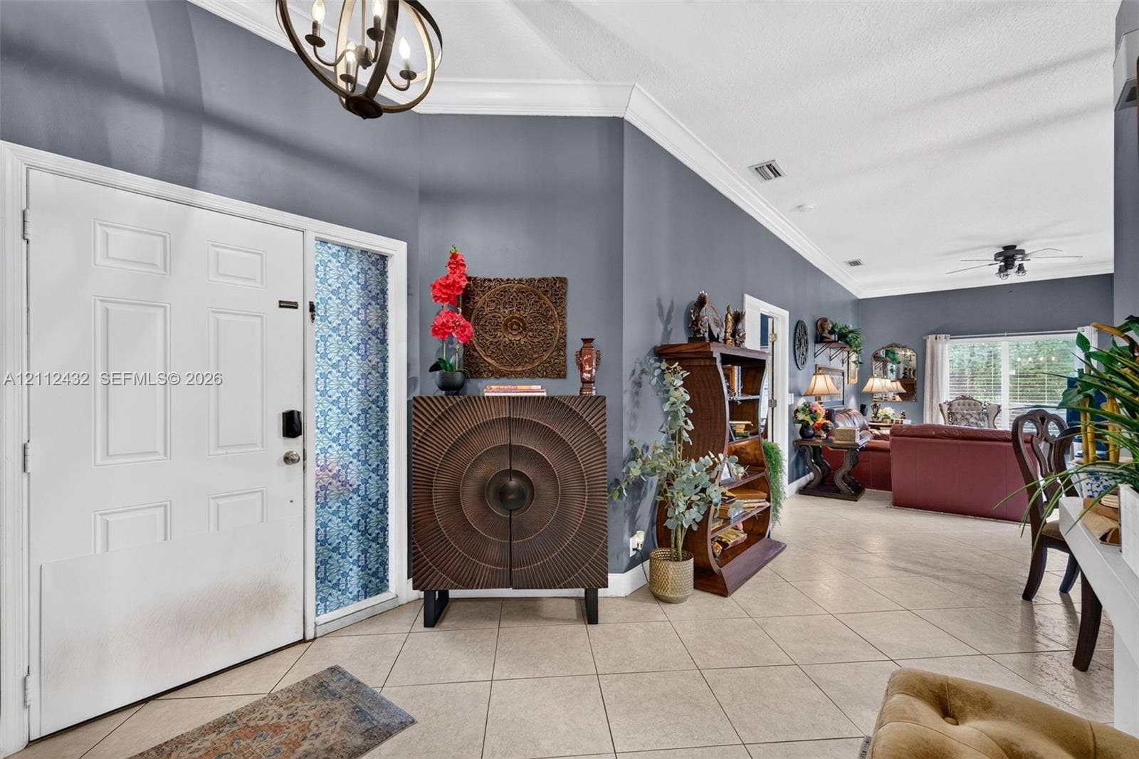 10545 NW 11th Court, Plantation, FL 33322 Foyer featuring a white front door with sidelight, vaulted ceilings with crown molding, light-toned ceramic tile flooring, and a decorative orb chandelier