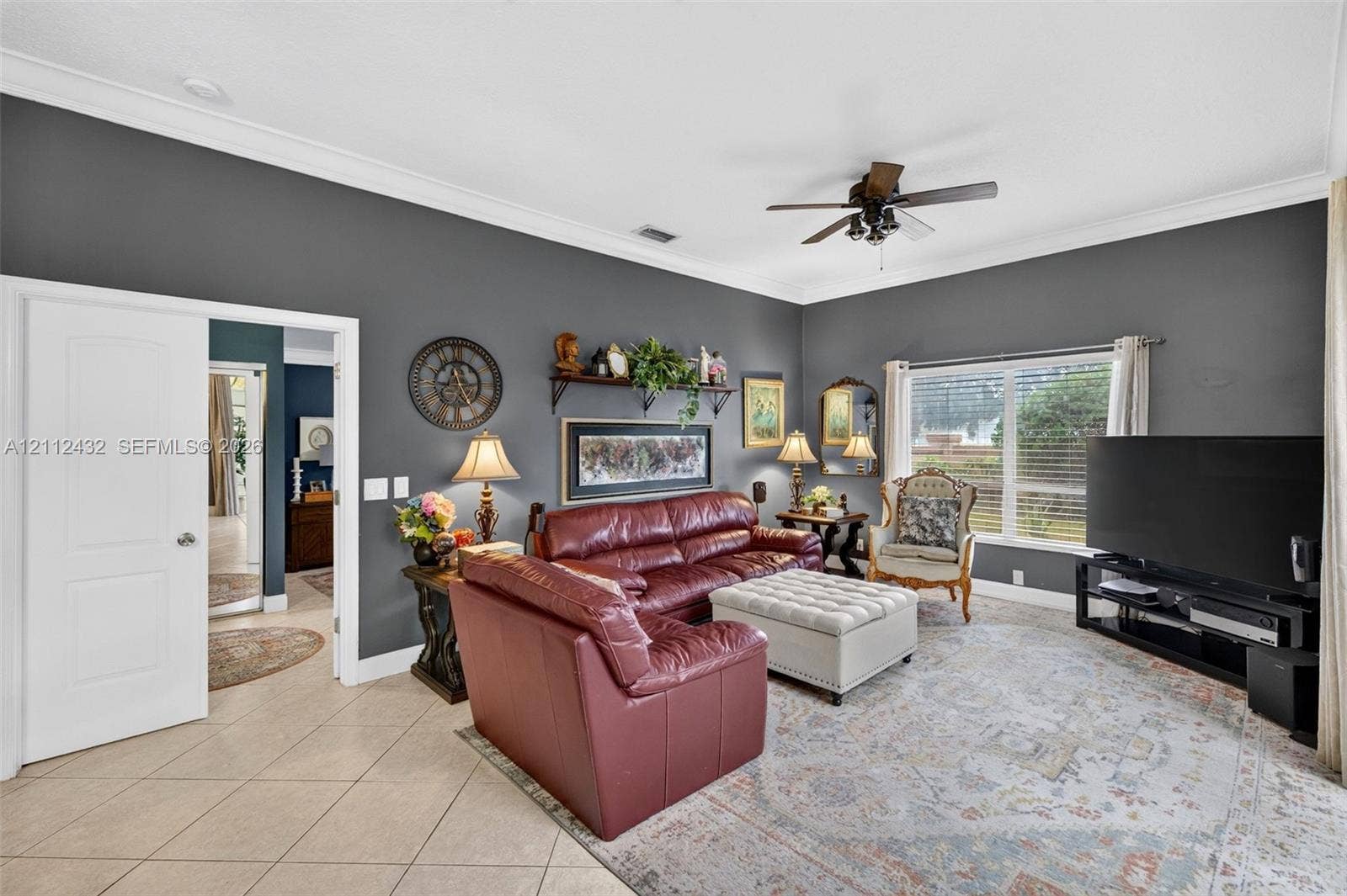 10545 NW 11th Court, Plantation, FL 33322 Living area featuring high ceilings with crown molding, neutral tile flooring, and a ceiling fan