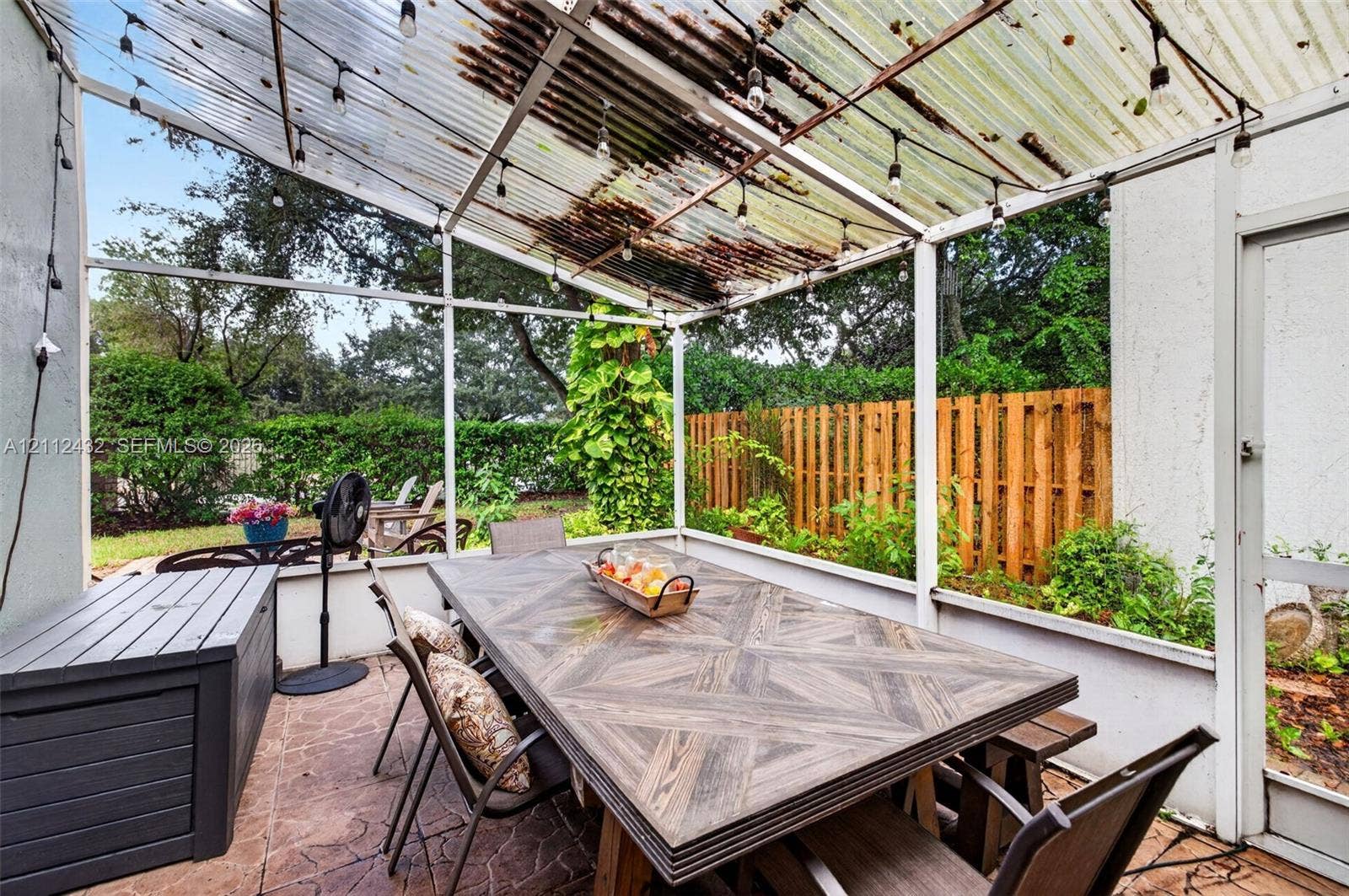 10545 NW 11th Court, Plantation, FL 33322 Screened-in patio featuring a textured tile floor, corrugated overhead covering, and screen enclosure