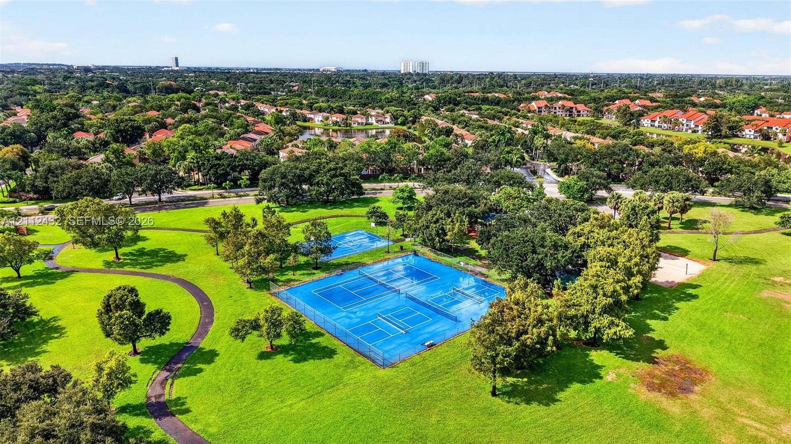 10545 NW 11th Court, Plantation, FL 33322 Extensive grounds featuring fenced tennis courts, winding paved paths, manicured lawns, and mature trees