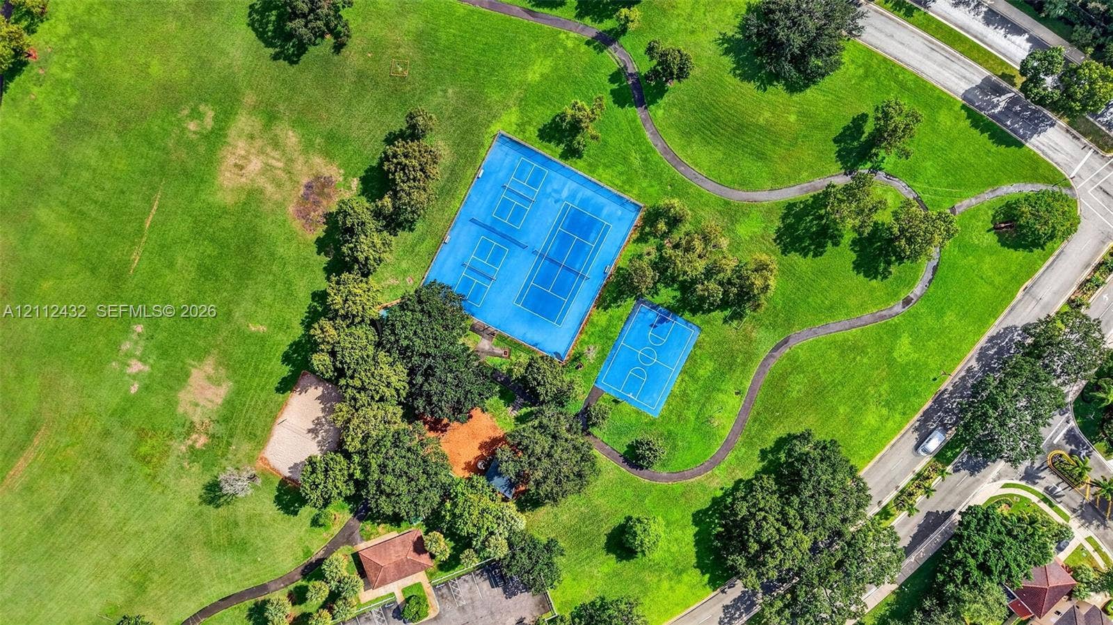 10545 NW 11th Court, Plantation, FL 33322 Expansive green space featuring tennis courts, a basketball court, paved pathways, and mature trees