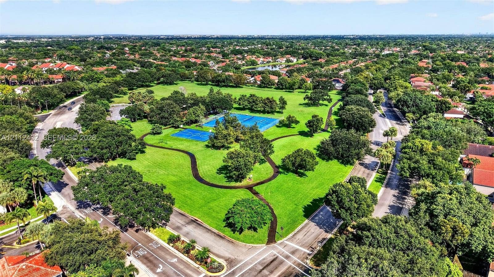 10545 NW 11th Court, Plantation, FL 33322 Aerial perspective of a sprawling park featuring multi-purpose paved recreation paths, blue-surface tennis courts, and mature landscaping