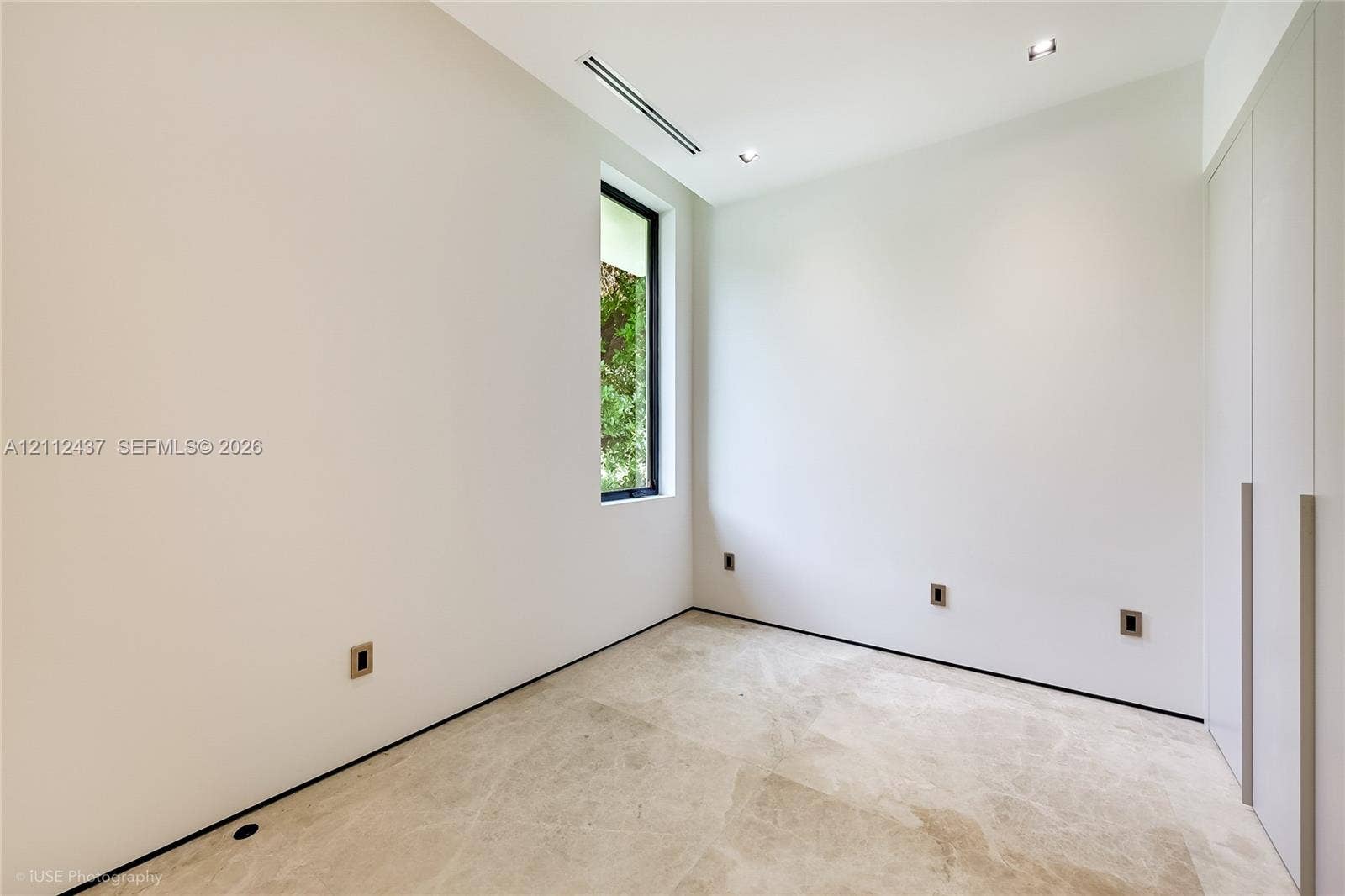 770 Lake Road, Miami, FL 33137 Minimalist room featuring natural stone flooring, floor-to-ceiling built-in cabinetry, recessed lighting, and a vertical window