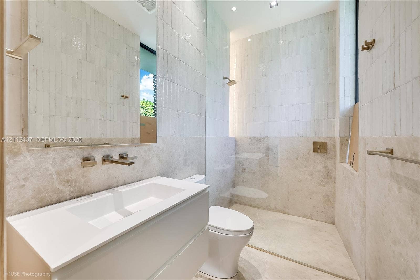 770 Lake Road, Miami, FL 33137 Floating vanity with integrated sink and wall-mounted faucet, walk-in shower with glass partition, floor-to-ceiling tiled walls, and recessed lighting