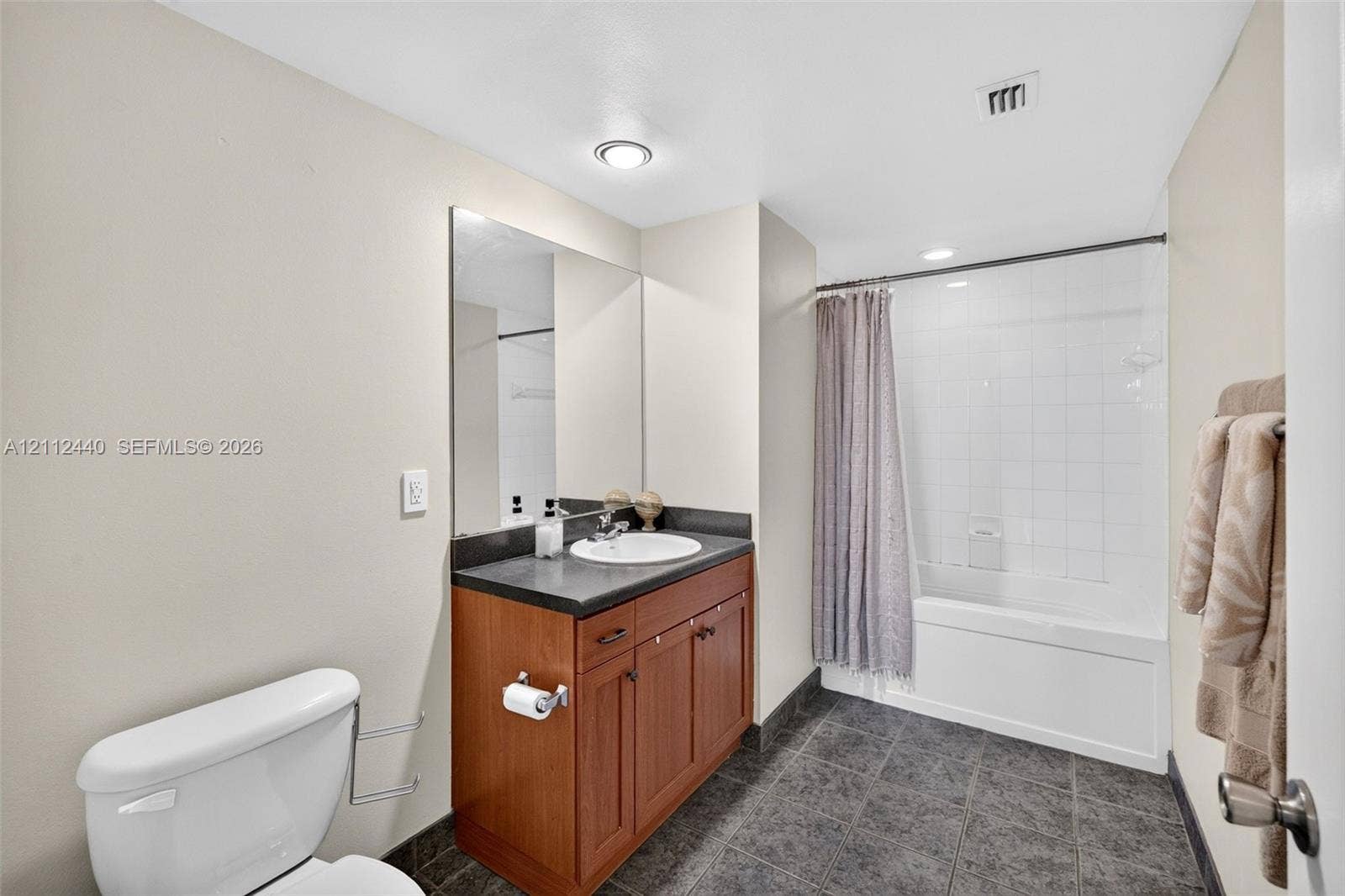 110 N Federal Highway, #914, Fort Lauderdale, FL 33301 Bathroom featuring a wood look finish vanity with a dark countertop, and a tiled tub-shower combination with dark tile flooring