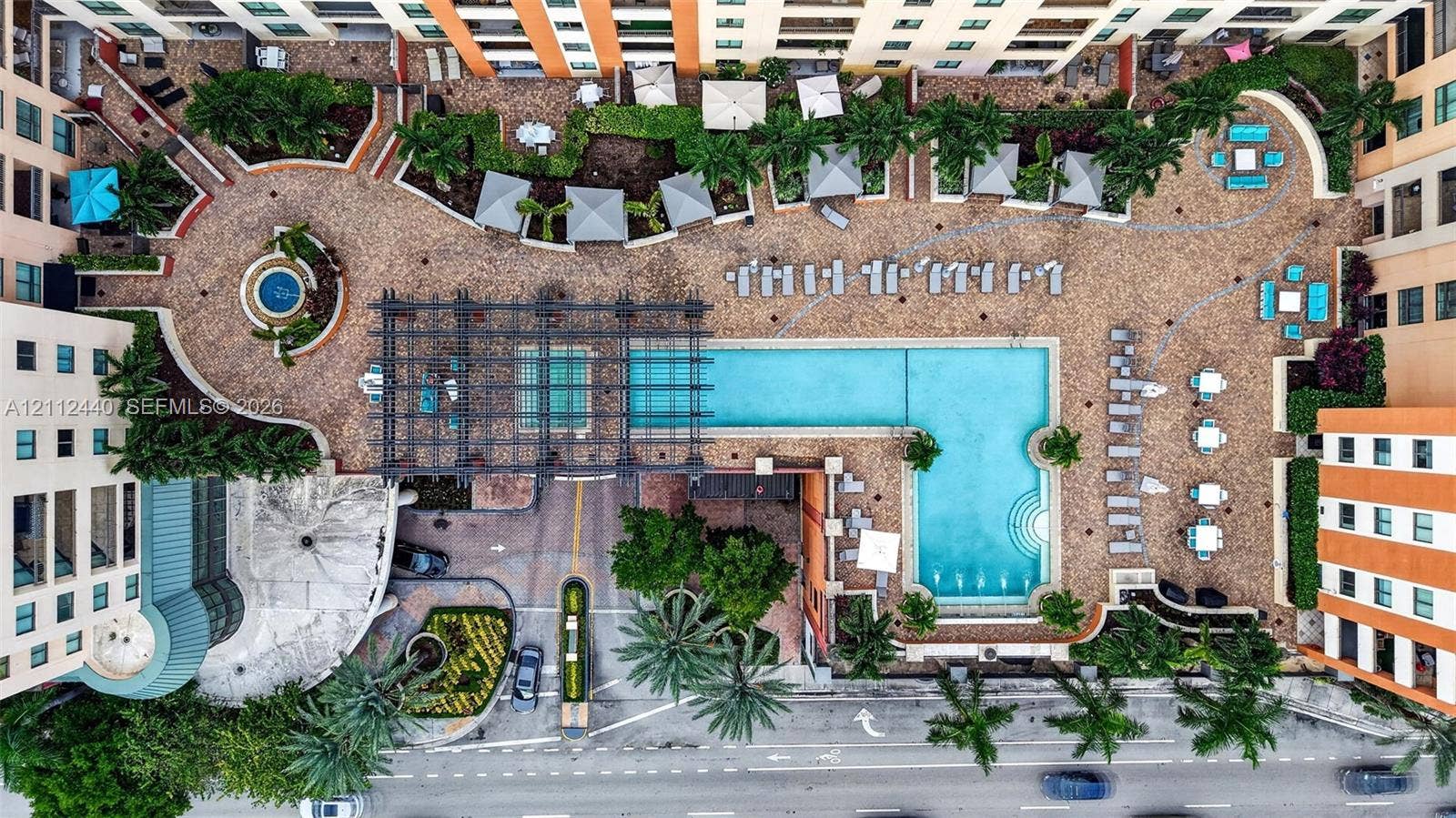 110 N Federal Highway, #914, Fort Lauderdale, FL 33301 Aerial view of an expansive swimming pool, metal pergola, paver hardscaping, built-in water feature, and mature palm landscaping