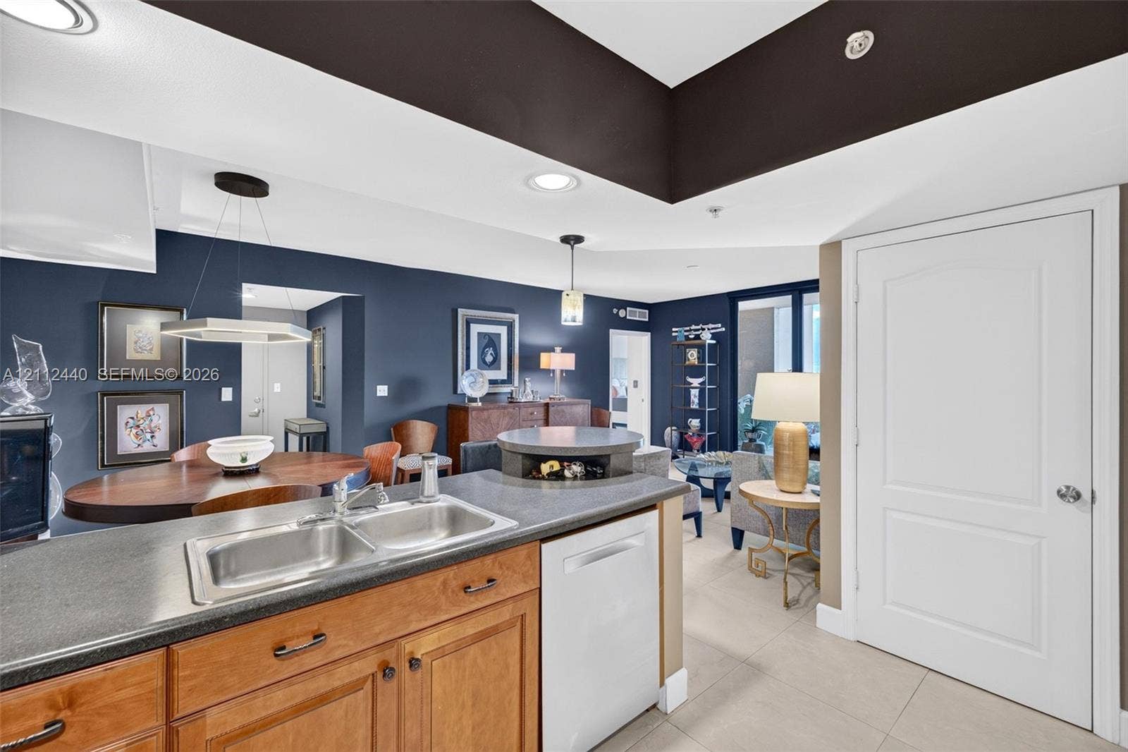 110 N Federal Highway, #914, Fort Lauderdale, FL 33301 Kitchen featuring wood cabinetry, dark countertops, dual-basin stainless sink, and integrated dishwasher, complemented by recessed and pendant lighting (dining fixture does not convey)