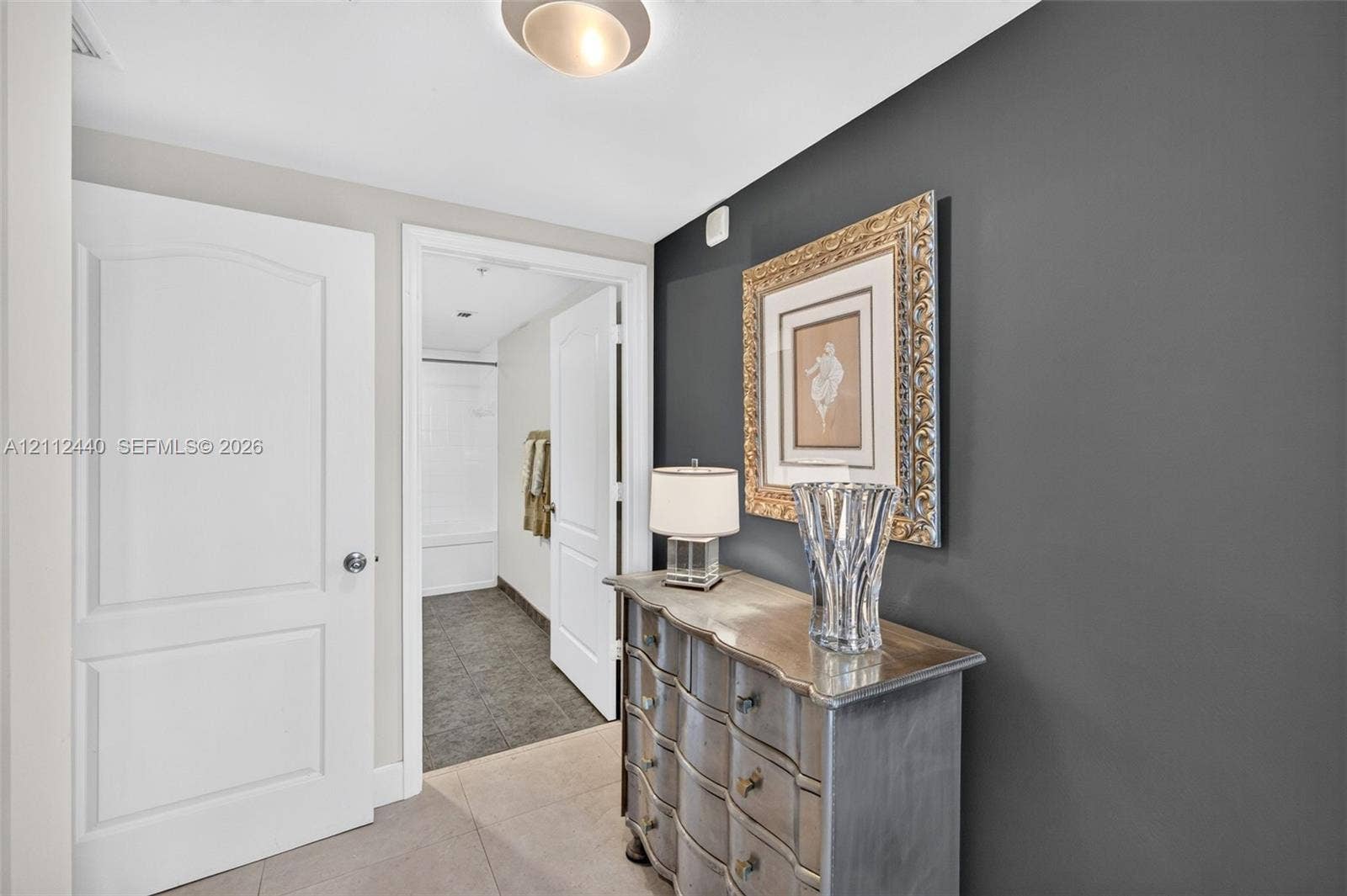 110 N Federal Highway, #914, Fort Lauderdale, FL 33301 Entrance to primary bedroom and ensuite bathroom, featuring a charcoal accent wall, neutral-toned porcelain flooring, flush-mount ceiling lighting