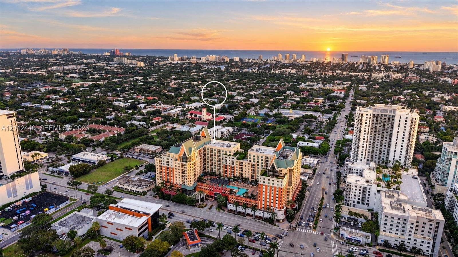 110 N Federal Highway, #914, Fort Lauderdale, FL 33301 Aerial perspective of a multi-story residential building featuring a swimming pool, courtyard terrace, pitched roofline, and coastal horizon backdrop