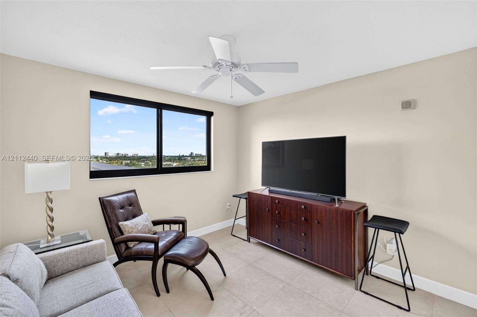 110 N Federal Highway, #914, Fort Lauderdale, FL 33301 Neutral-toned room featuring a large window with black framing, tile flooring, and a white ceiling fan with integrated lighting
