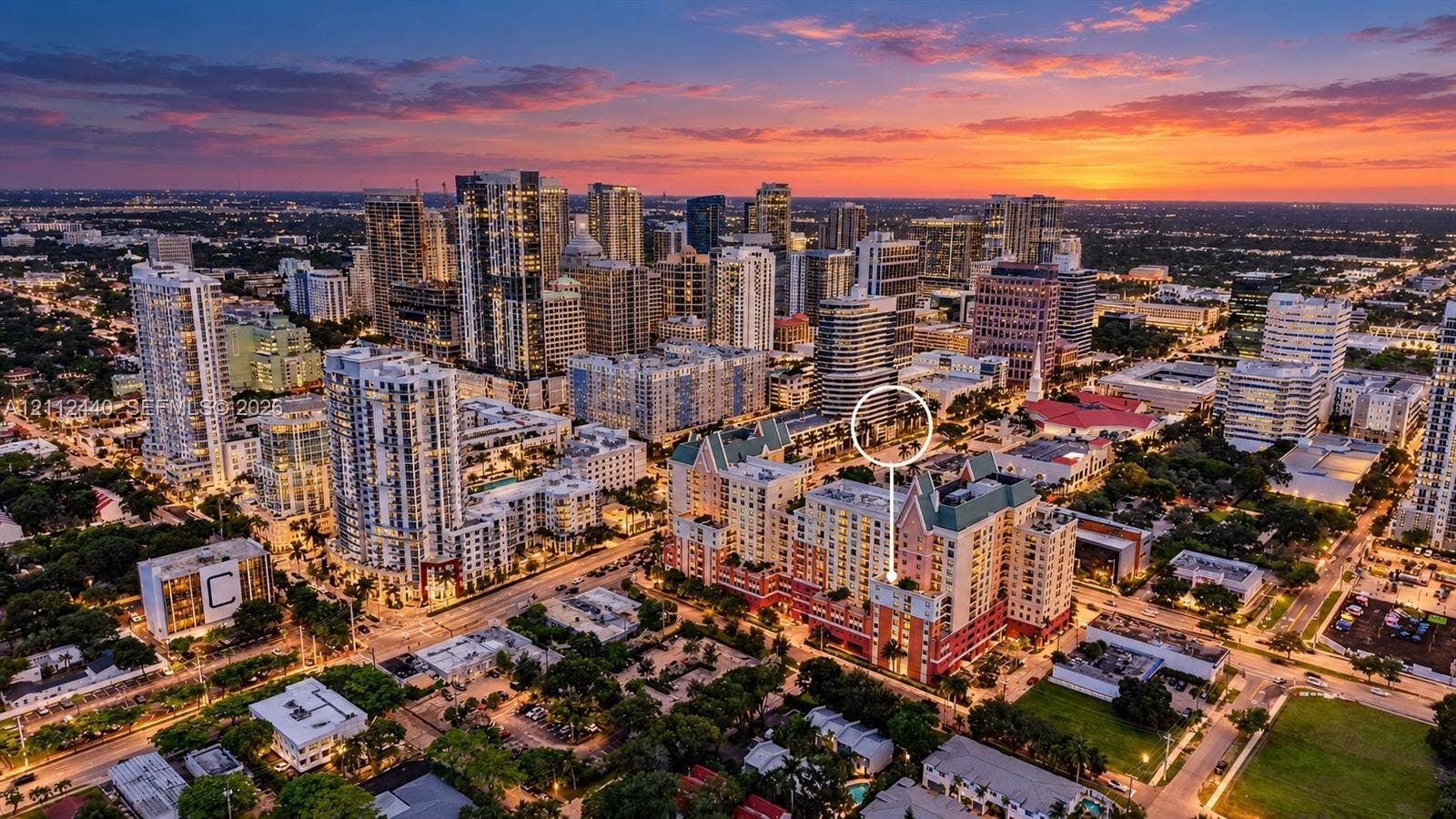 110 N Federal Highway, #914, Fort Lauderdale, FL 33301 Aerial perspective of a multi-story building featuring a pitched green roof, balconies, and a terracotta-toned facade situated within a dense urban skyline