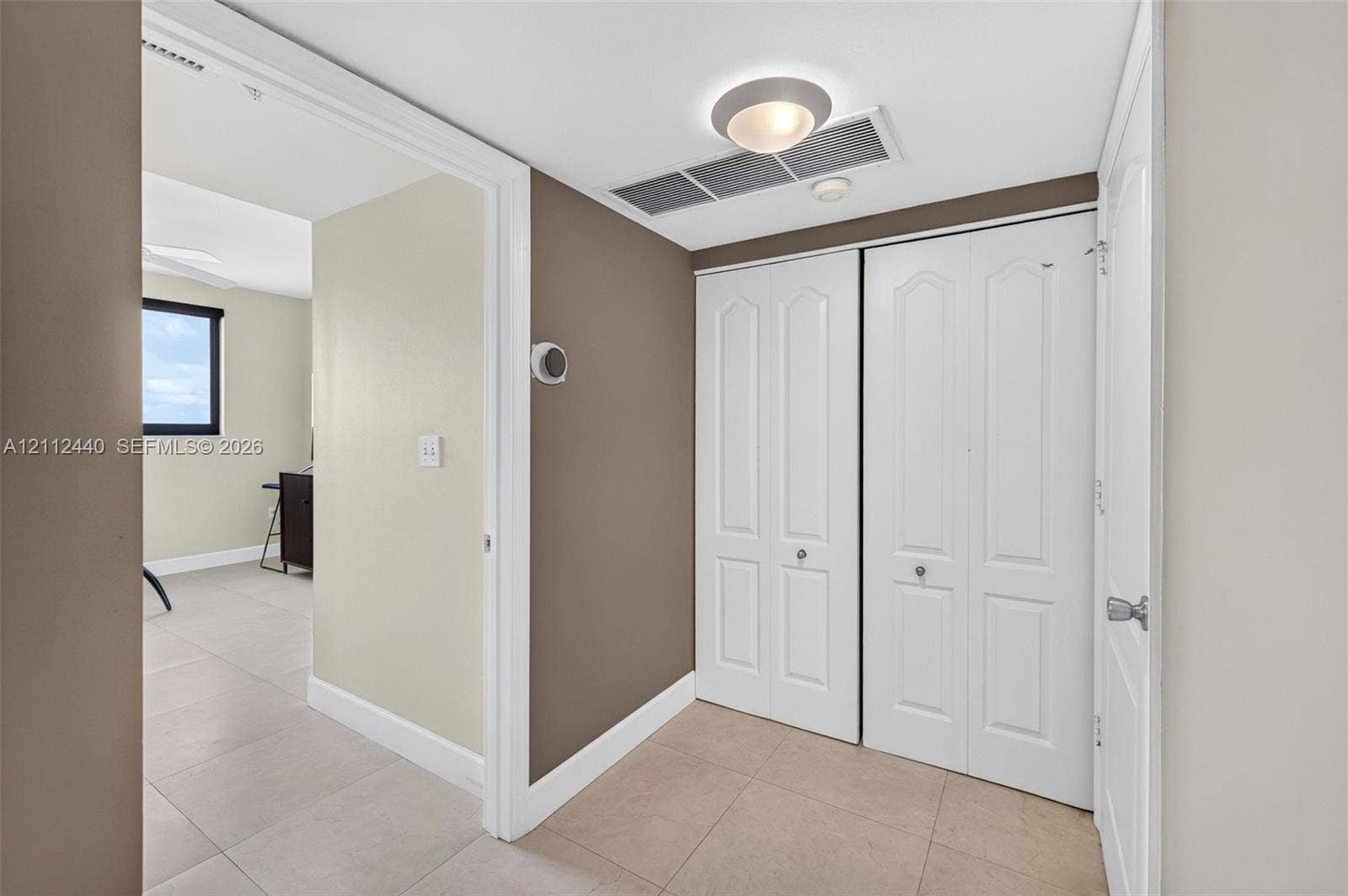 110 N Federal Highway, #914, Fort Lauderdale, FL 33301 Neutral-toned interior space between guest bedroom and bathroom featuring large-format tile flooring, double-panel bifold closet doors w/ pantry storage area