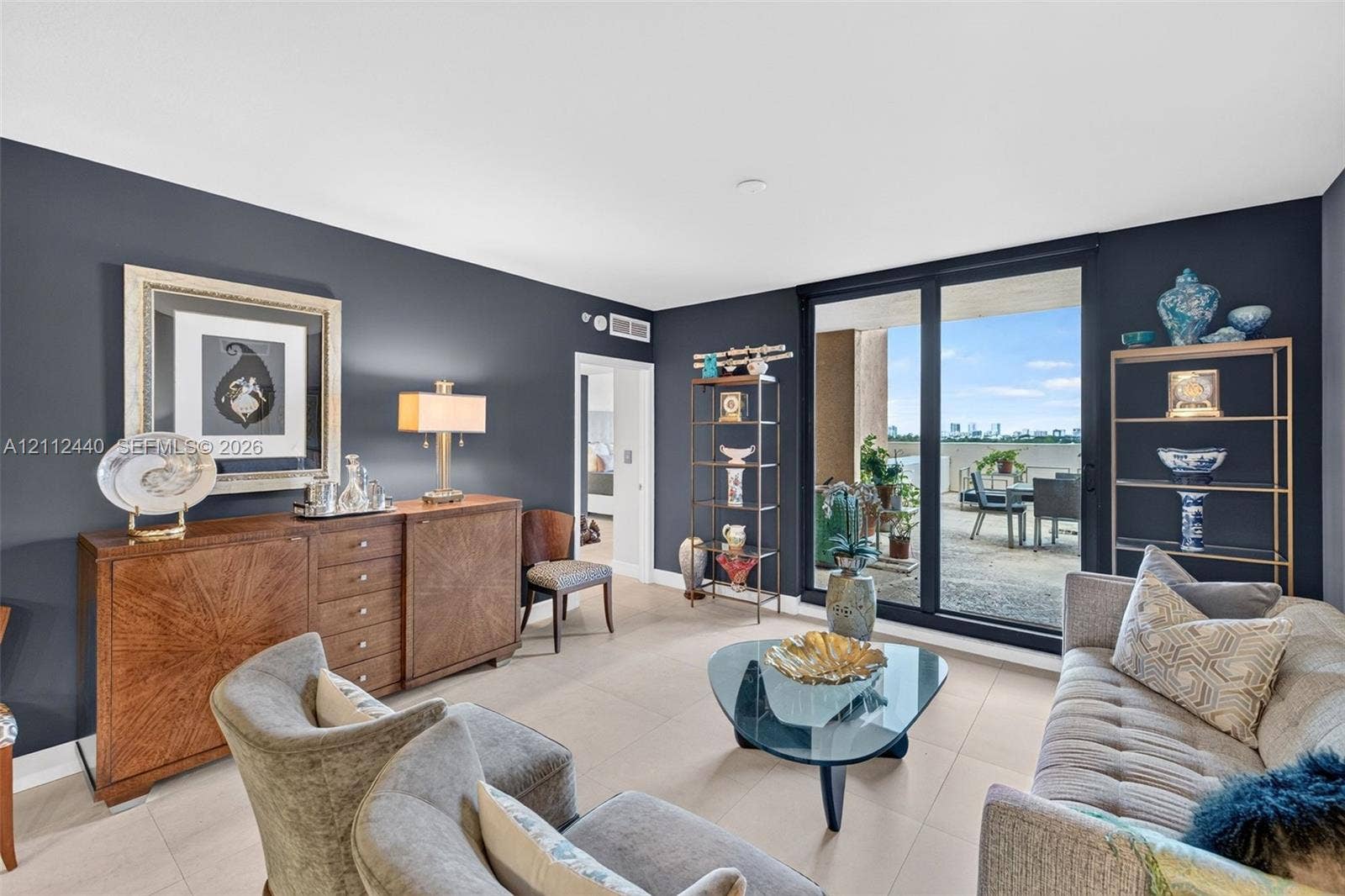 110 N Federal Highway, #914, Fort Lauderdale, FL 33301 Living area with light-toned porcelain flooring, deep-toned accent walls, and floor-to-ceiling sliding glass doors opening to a huge concrete balcony w/ condo views by the beach