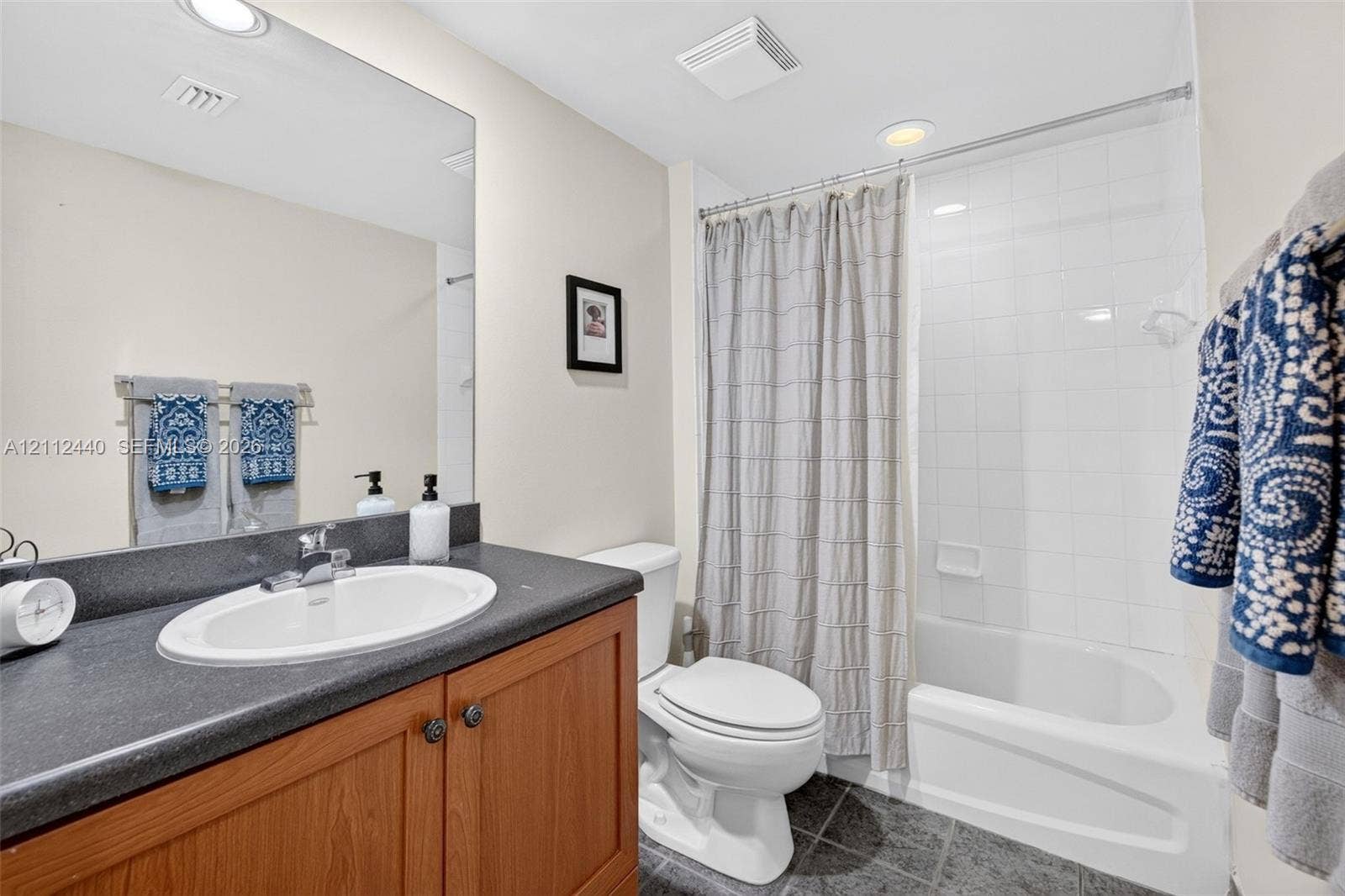 110 N Federal Highway, #914, Fort Lauderdale, FL 33301 Bathroom featuring a wood look vanity, dark counter, recessed lighting, and a white tiled tub/shower surround
