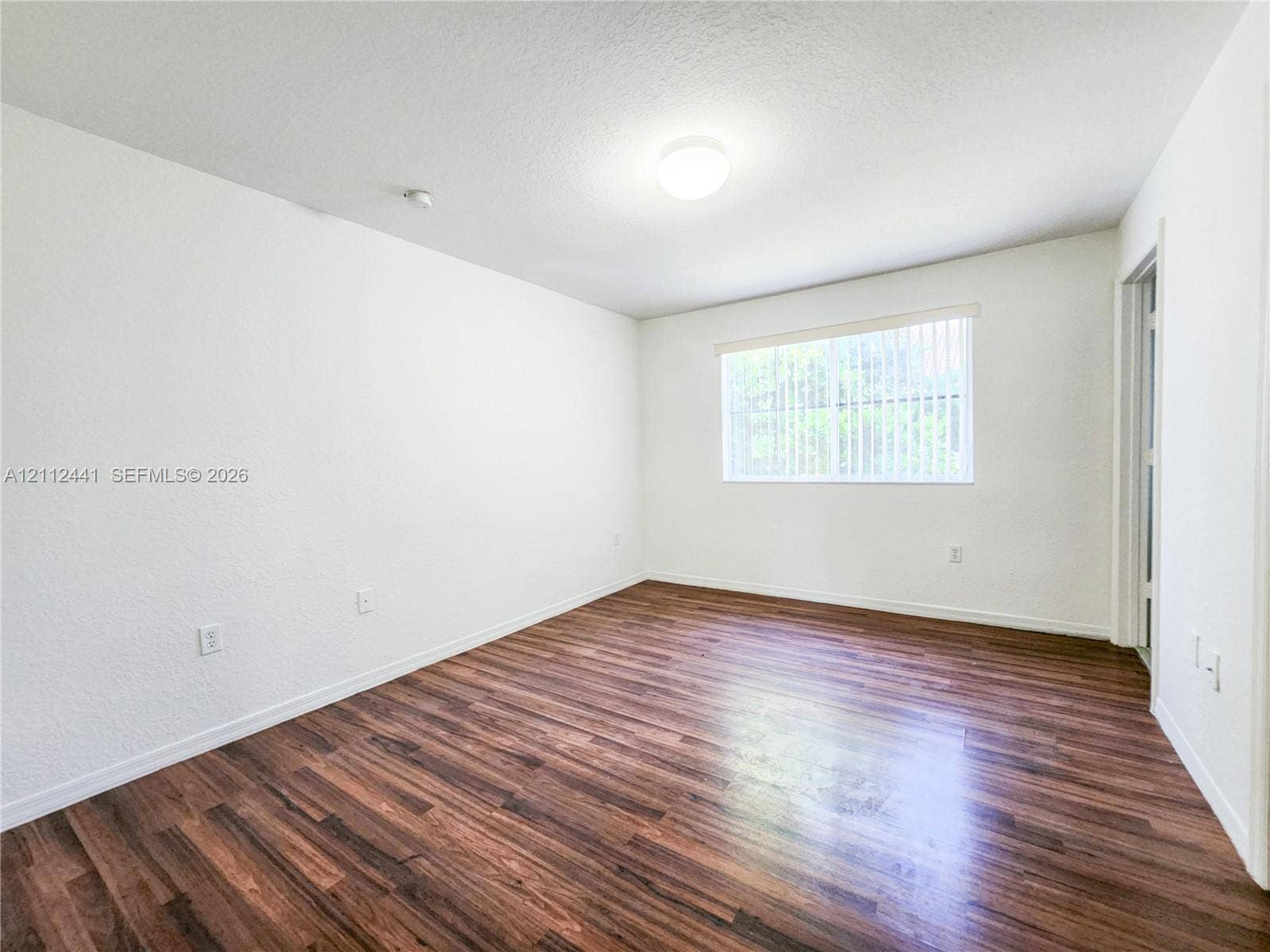 Interior space featuring wood-finish flooring, white walls, and a recessed ceiling light fixture