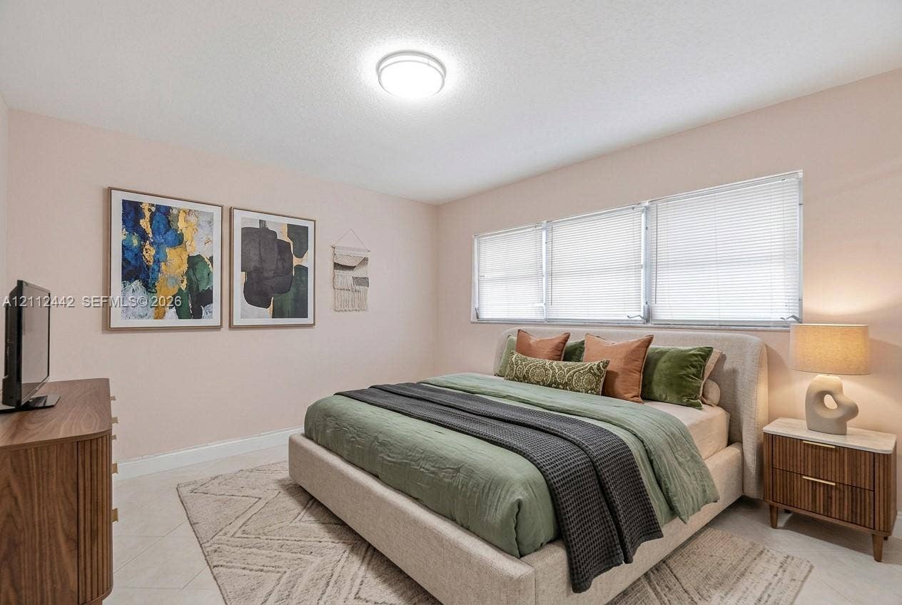 2455 NE 51st Street, #E114, Fort Lauderdale, FL 33308 Bedroom featuring light-toned neutral wall paint, tile flooring, and horizontal window blinds