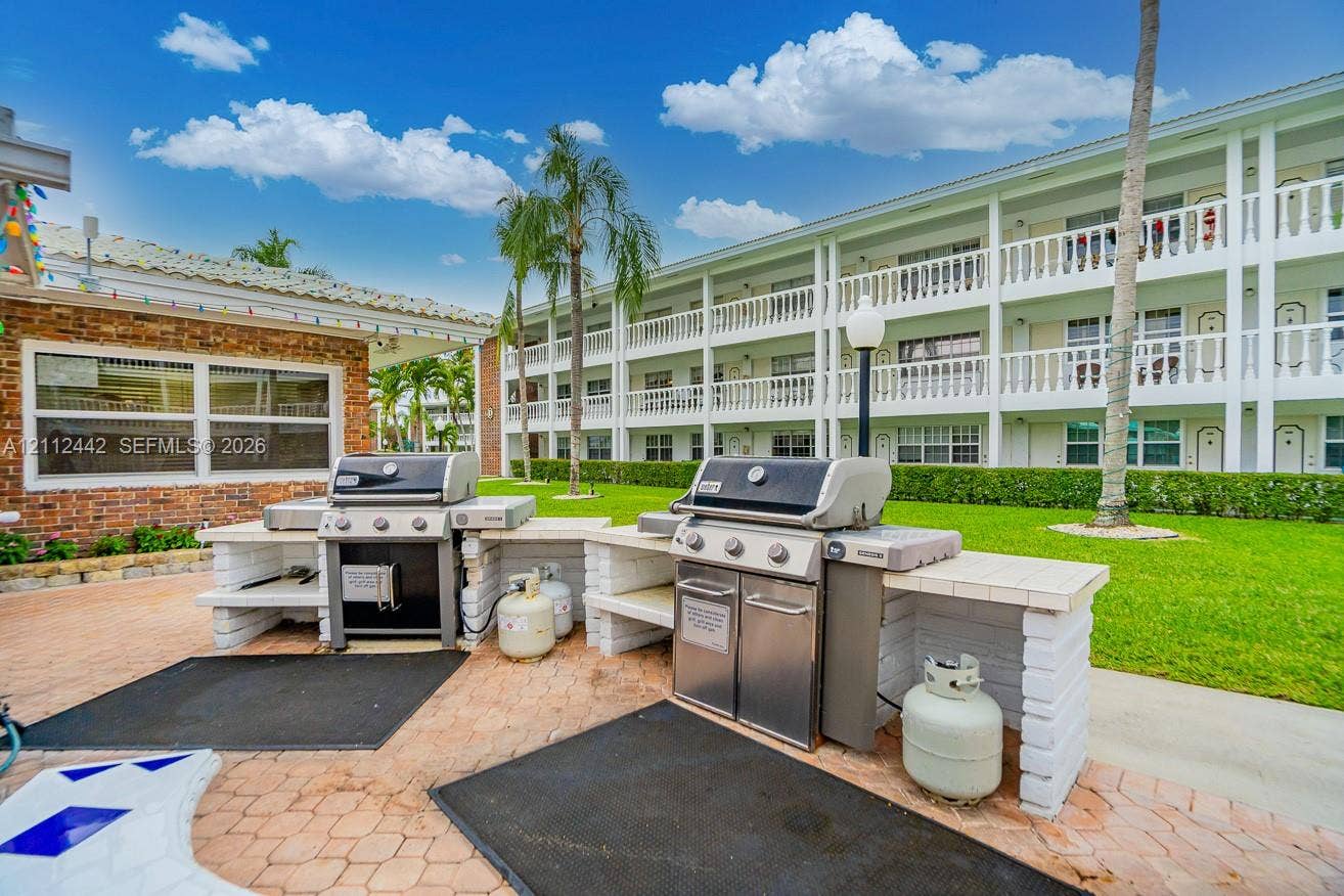 2455 NE 51st Street, #E114, Fort Lauderdale, FL 33308 Outdoor grilling area featuring two stainless steel gas grills, built-in masonry counters, and paver patio flooring