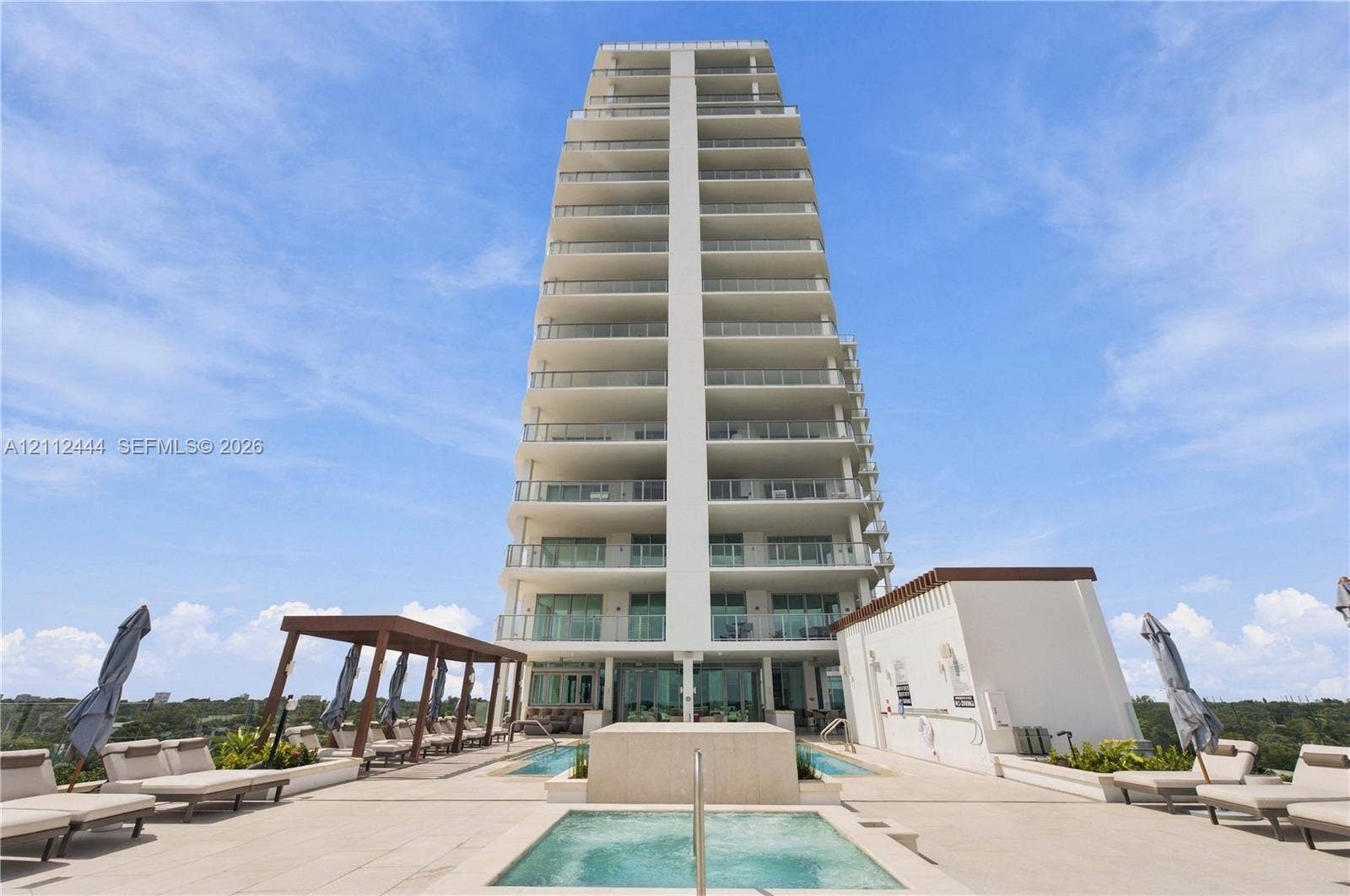 High-rise building exterior featuring tiered balconies with metal railings, elevated terrace level, tiled sundeck, built-in swimming pool, and custom pergola structure