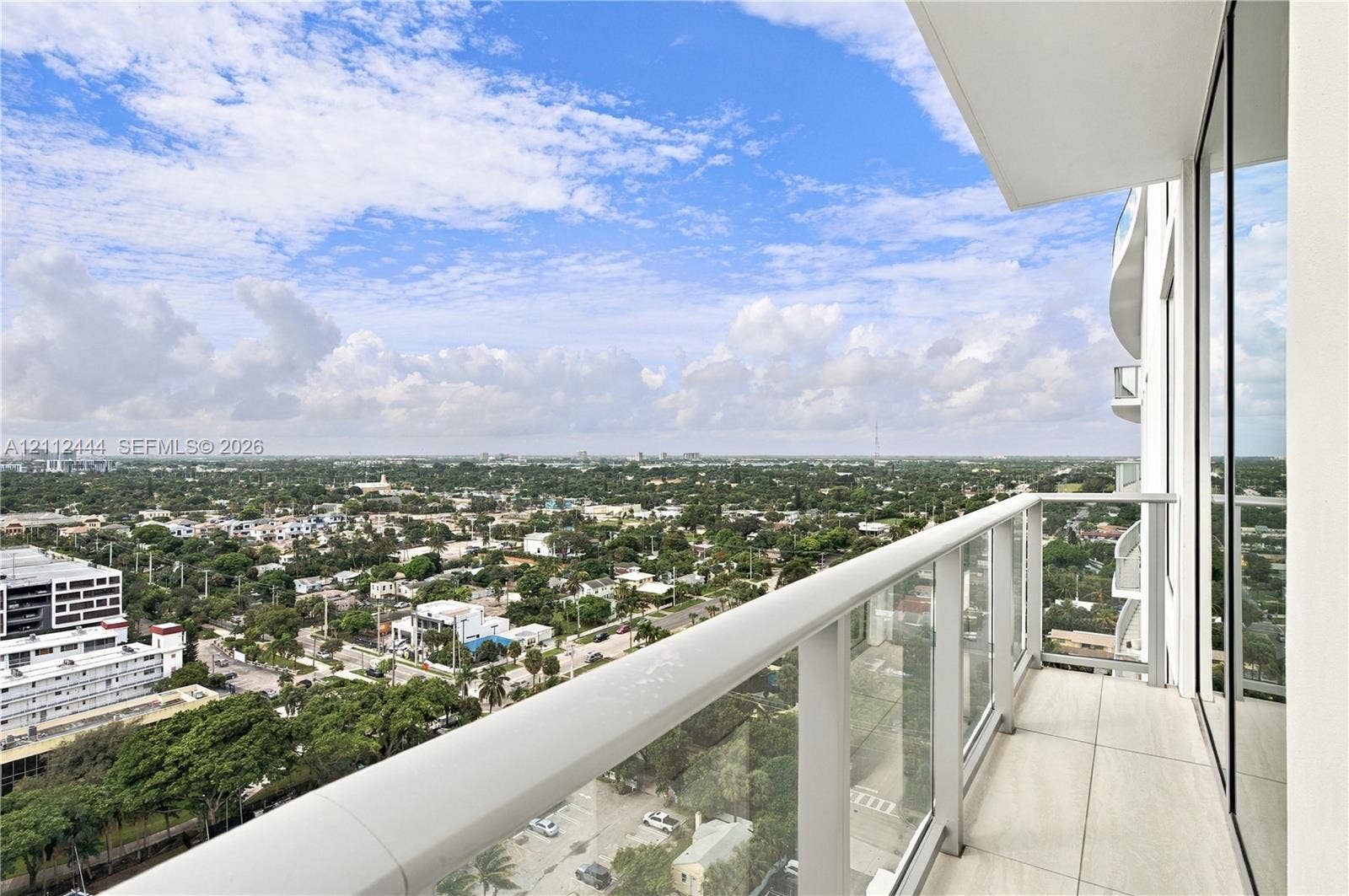 Private balcony featuring large-format tile flooring, glass panel railings, and full-height sliding glass doors