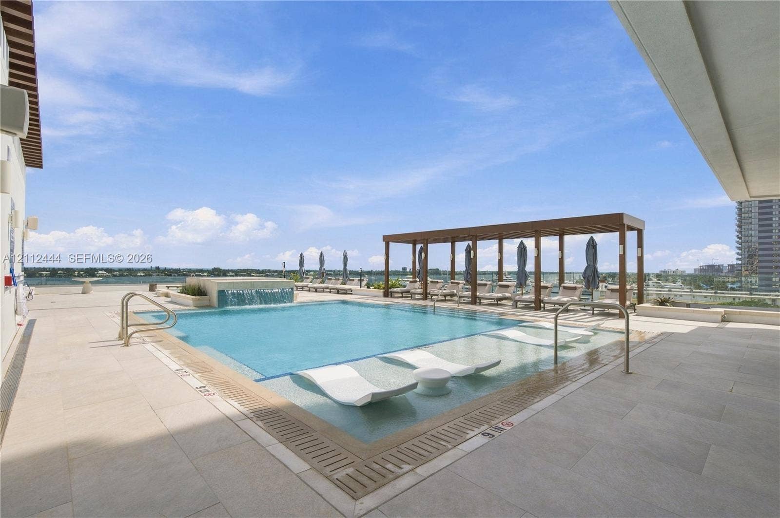 Rooftop pool featuring a water feature, baja shelf, large-format tile decking, and a wood-finish pergola