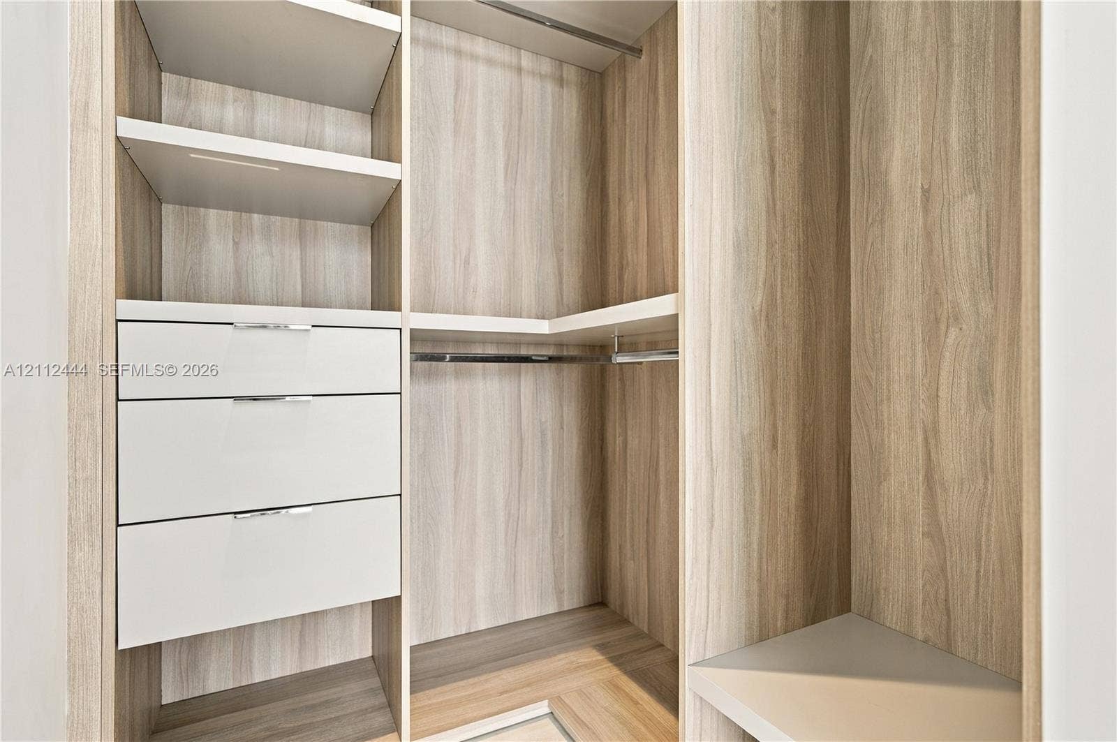 Custom walk-in closet featuring wood-finish cabinetry, open shelving, integrated drawers with metal pulls, and built-in hanging rods