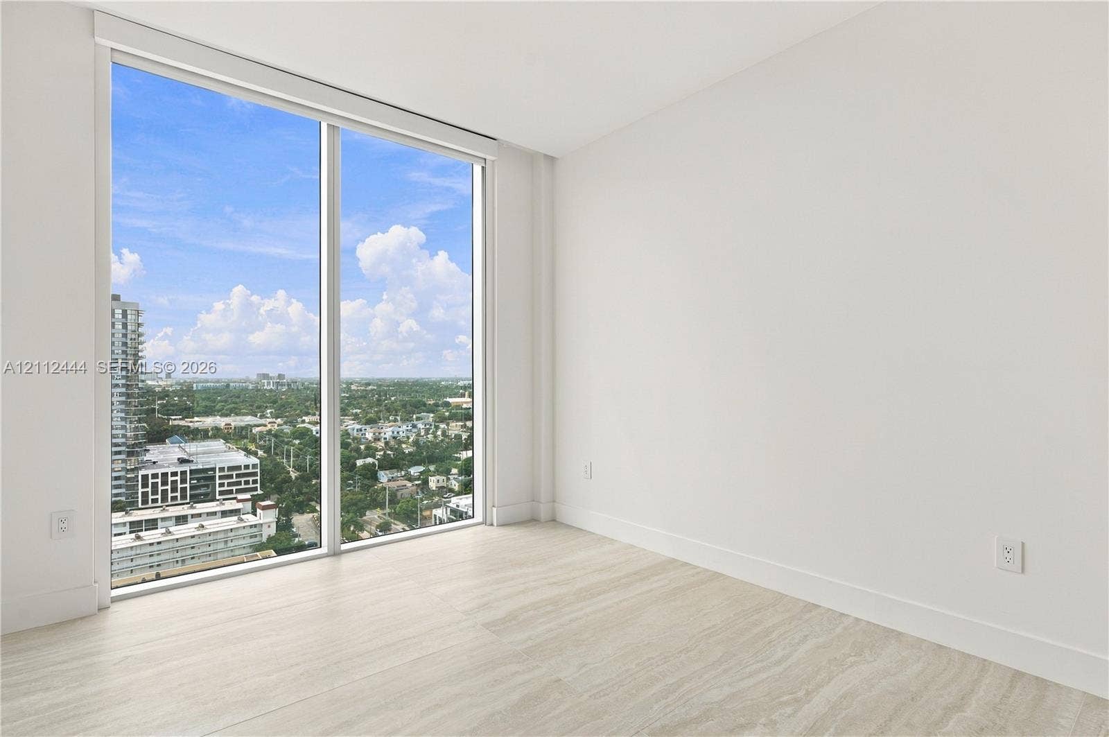 Floor-to-ceiling windows, neutral interior walls, and stone-finish flooring