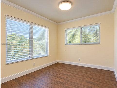 Room featuring wood-finish flooring, crown molding, two windows with horizontal blinds, and a flush-mount ceiling light