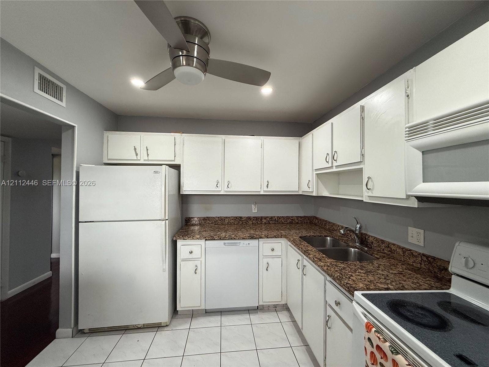 6100 S Falls Cir Drive, #411, Lauderhill, FL 33319 Kitchen featuring white cabinetry, stone-surface countertops, dual-basin stainless steel sink, tile flooring, and a ceiling-mounted fan