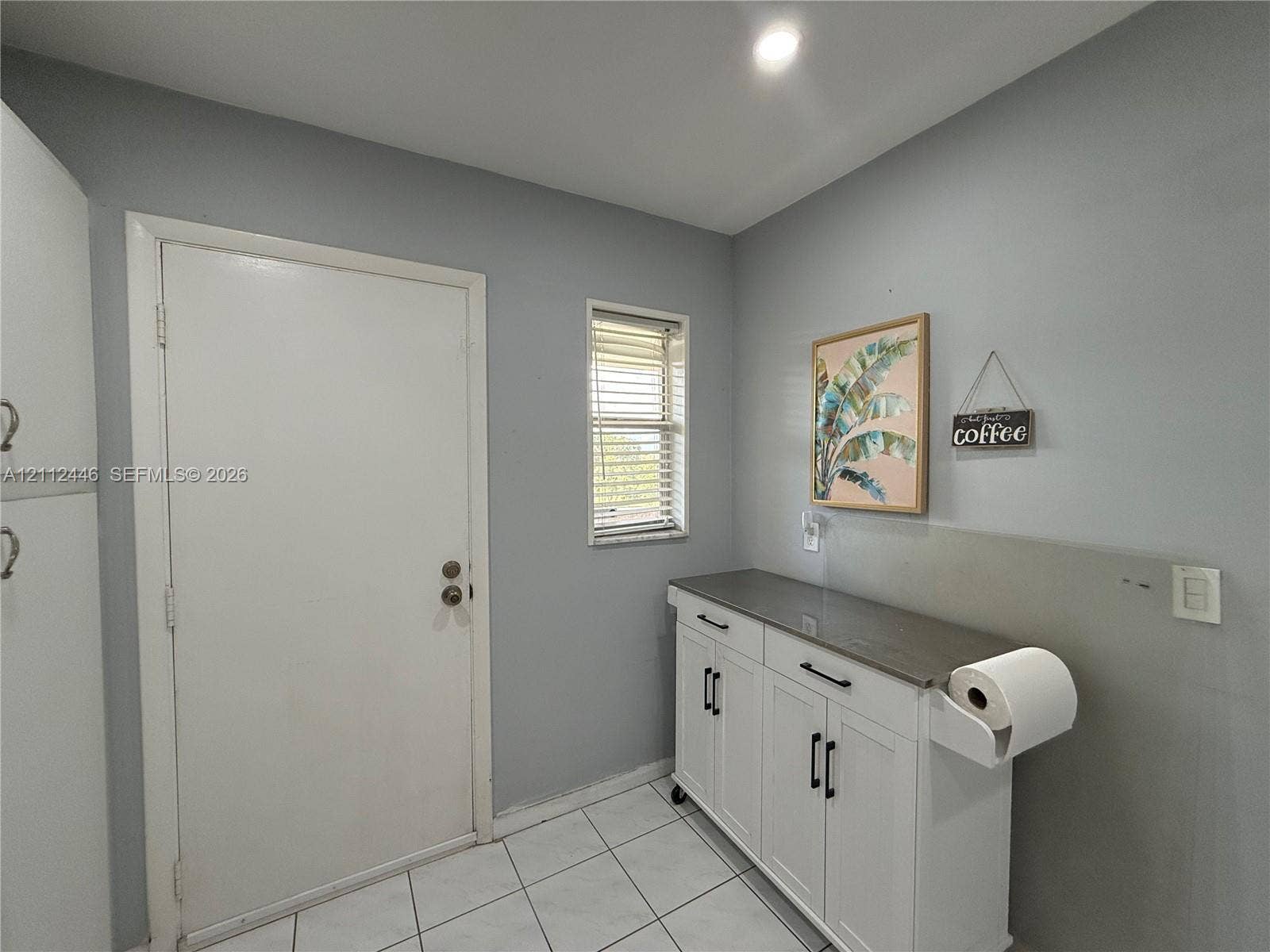 6100 S Falls Cir Drive, #411, Lauderhill, FL 33319 White cabinetry featuring dark hardware and a solid surface countertop, tile flooring, and a single-panel door